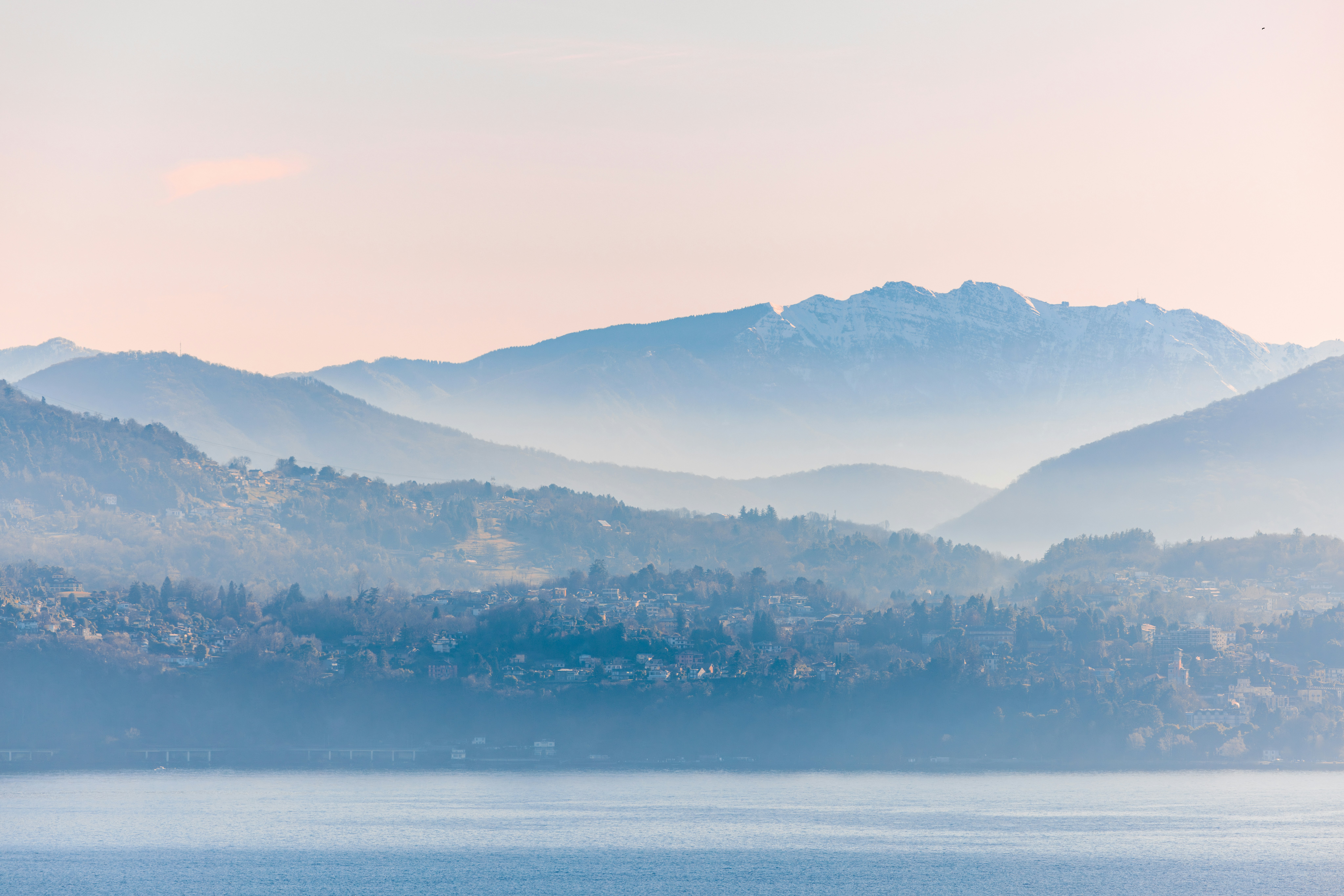 Layered blue mountains fade into a soft pink sky.