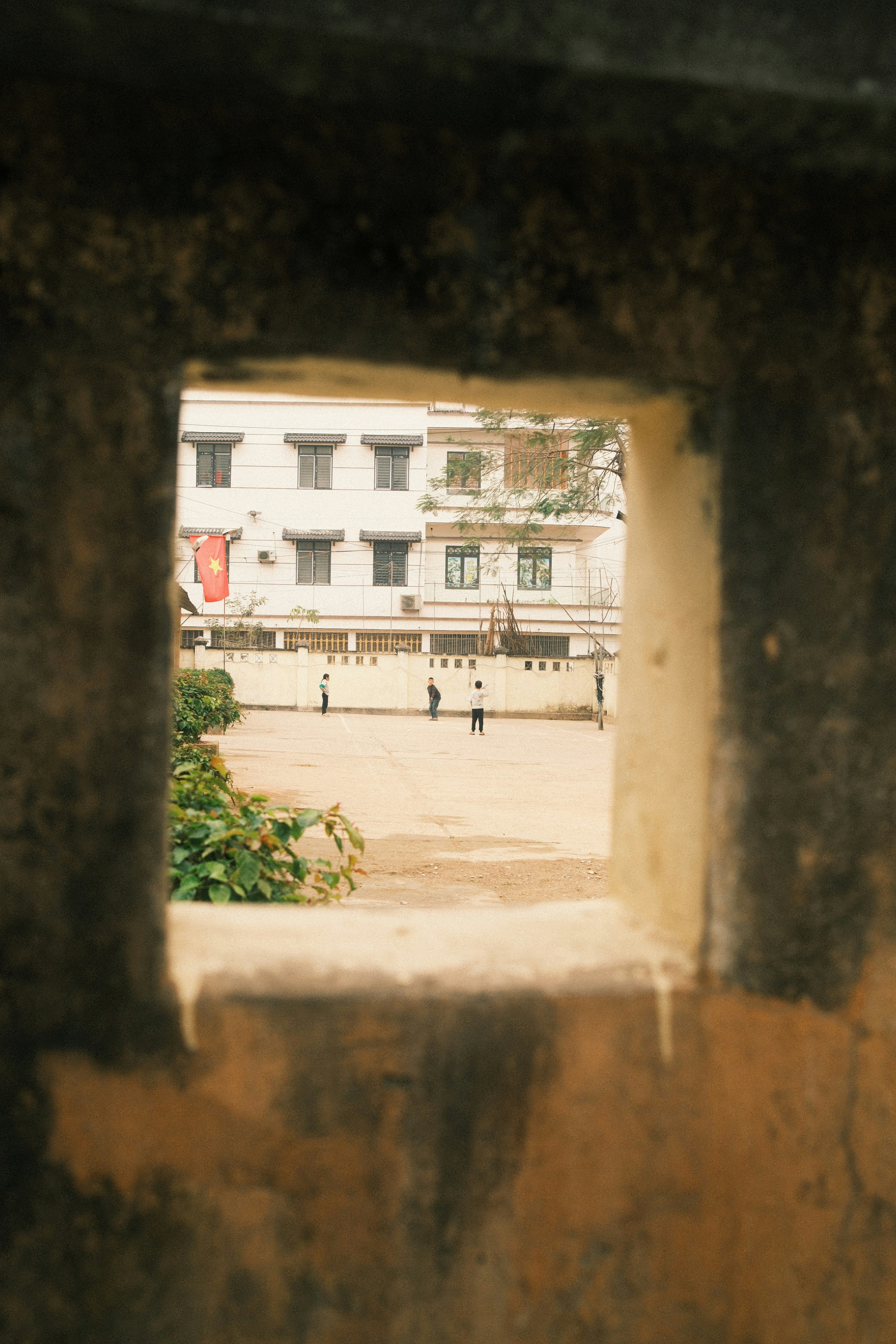 View through a square opening of a courtyard with people.