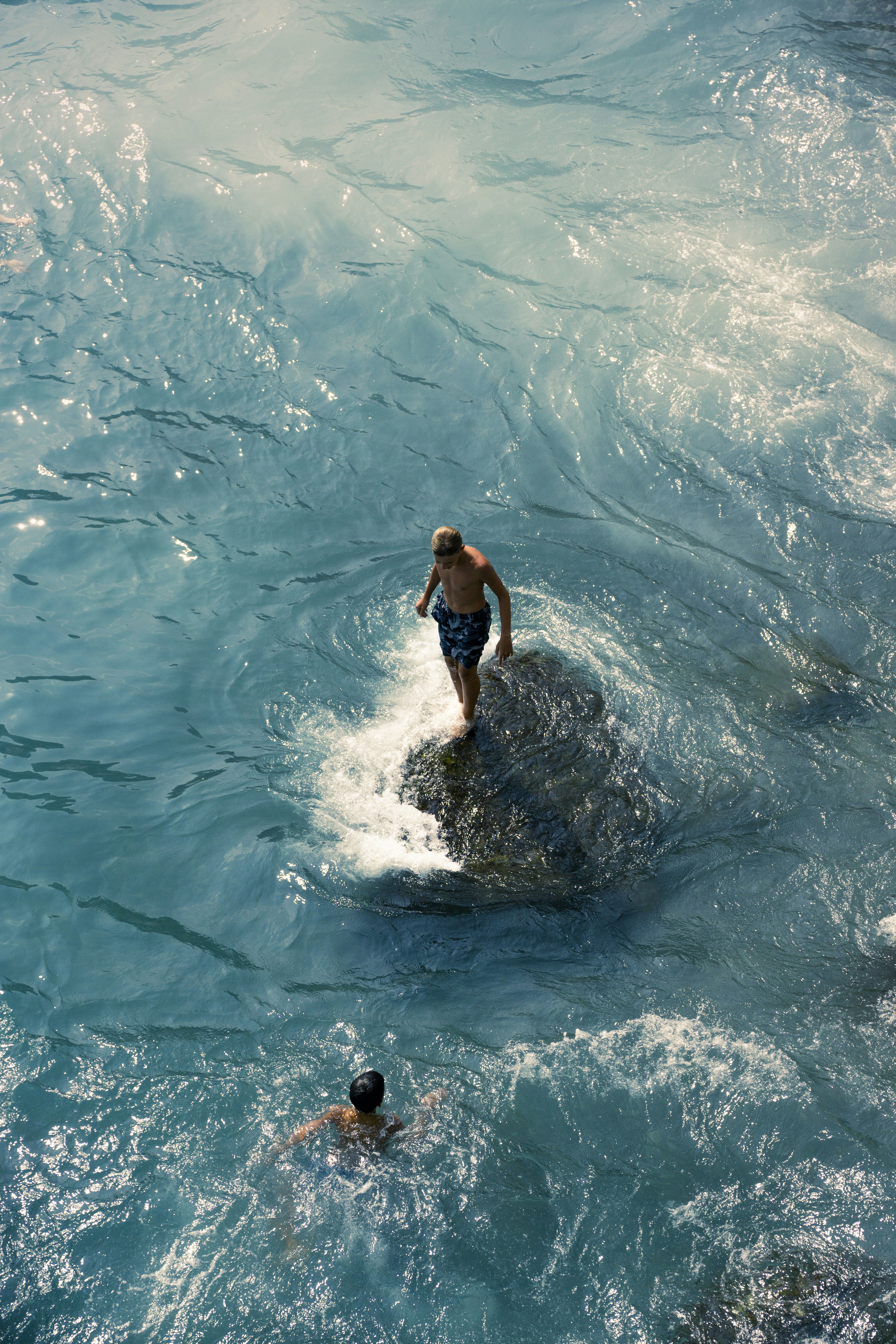 Man stands on rock in choppy blue water
