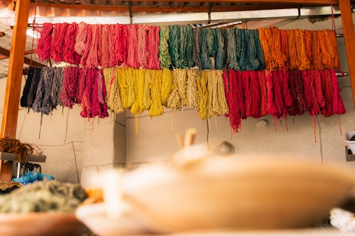 Colorful yarns drying on racks indoors.