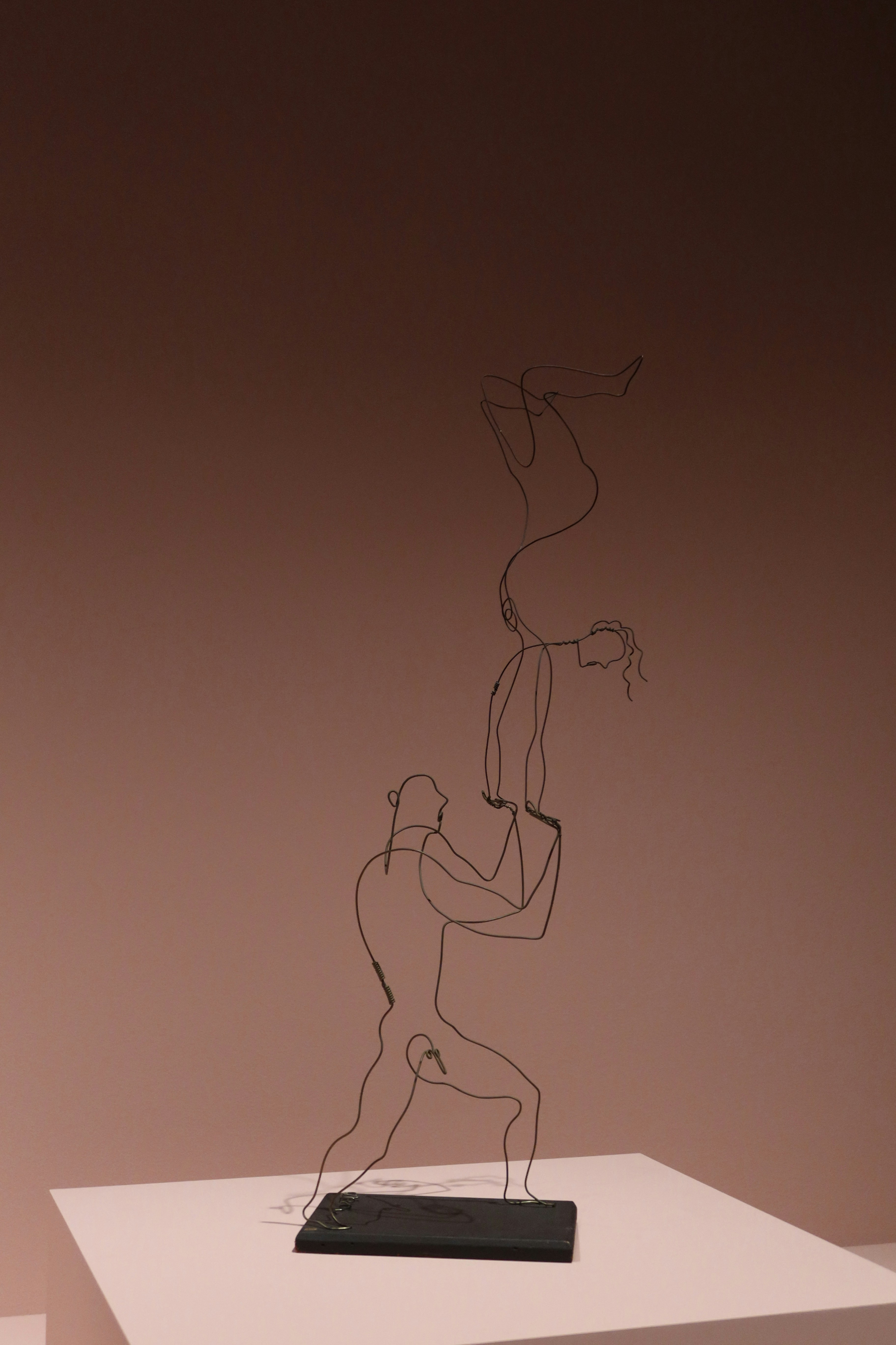 Wire sculpture of two acrobats balancing on each other.