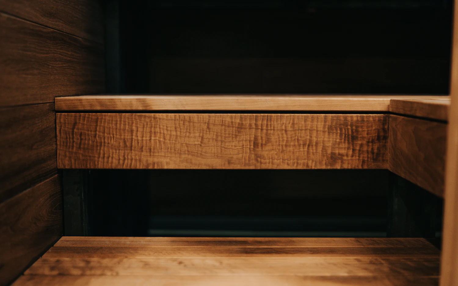 A thick figured maple shelf housed into a dark painted recess