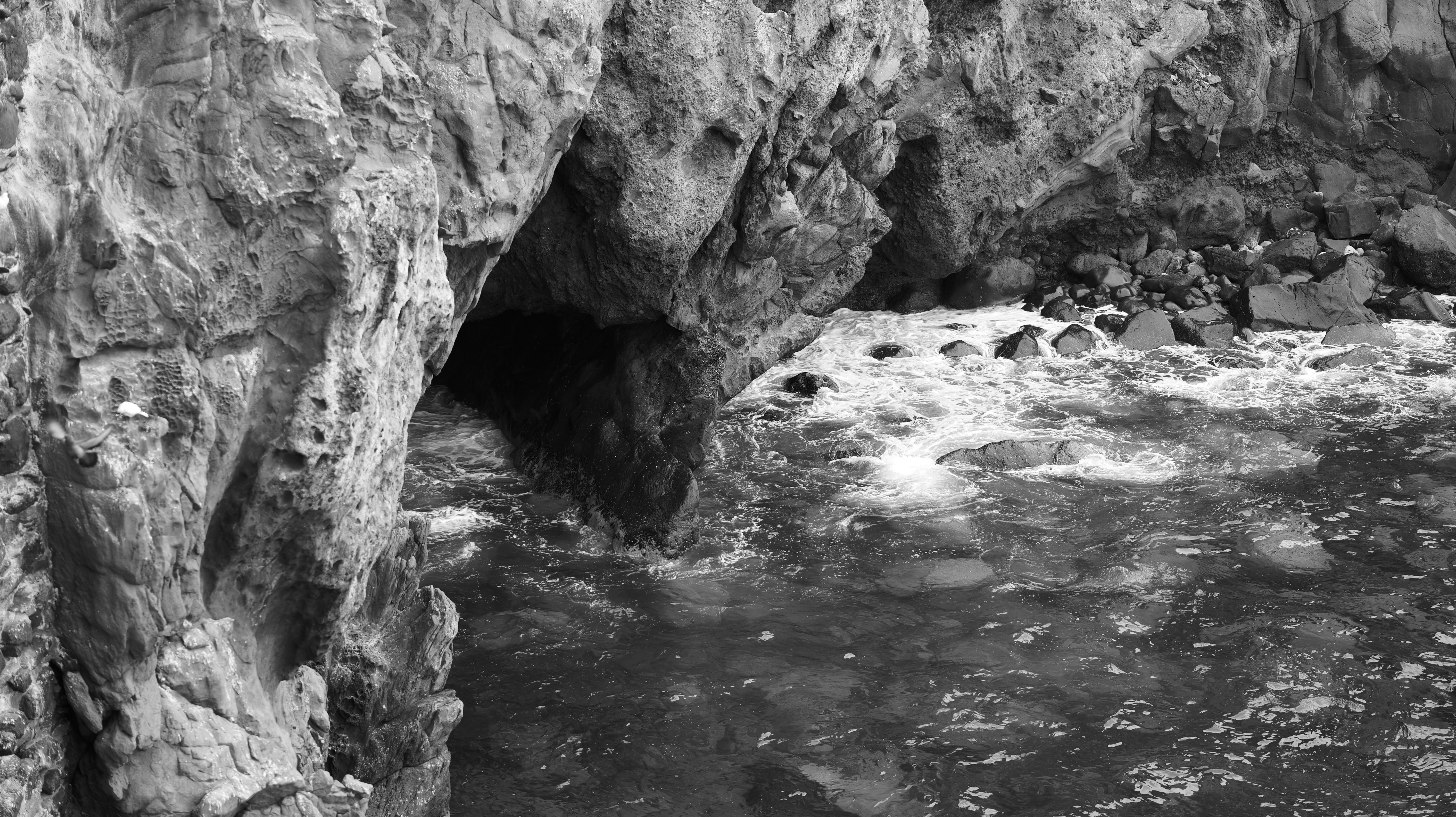 Rocky cave entrance with waves crashing inside