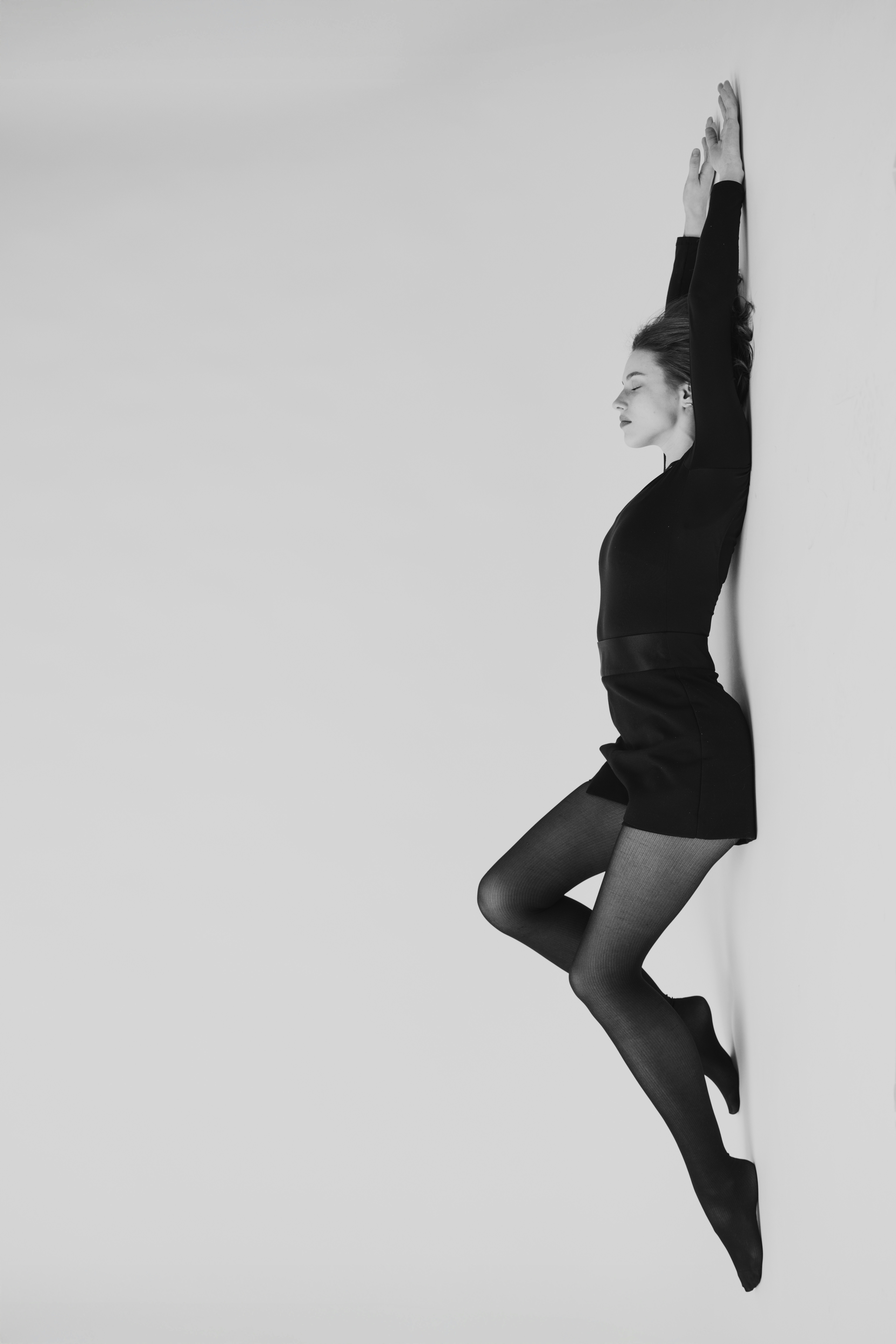 A woman leans against a wall with arms raised