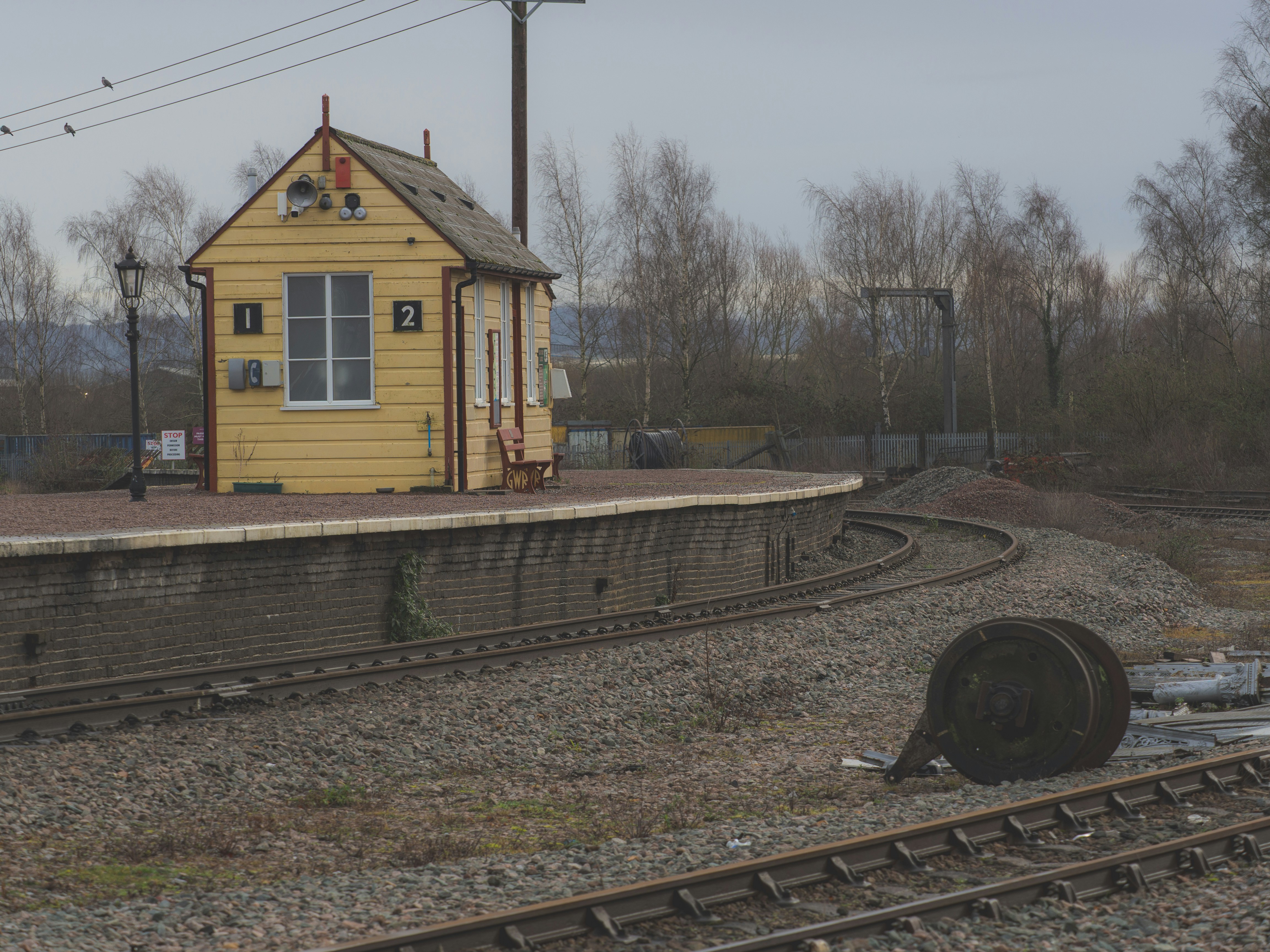 A yellow signal box stands beside railway tracks.