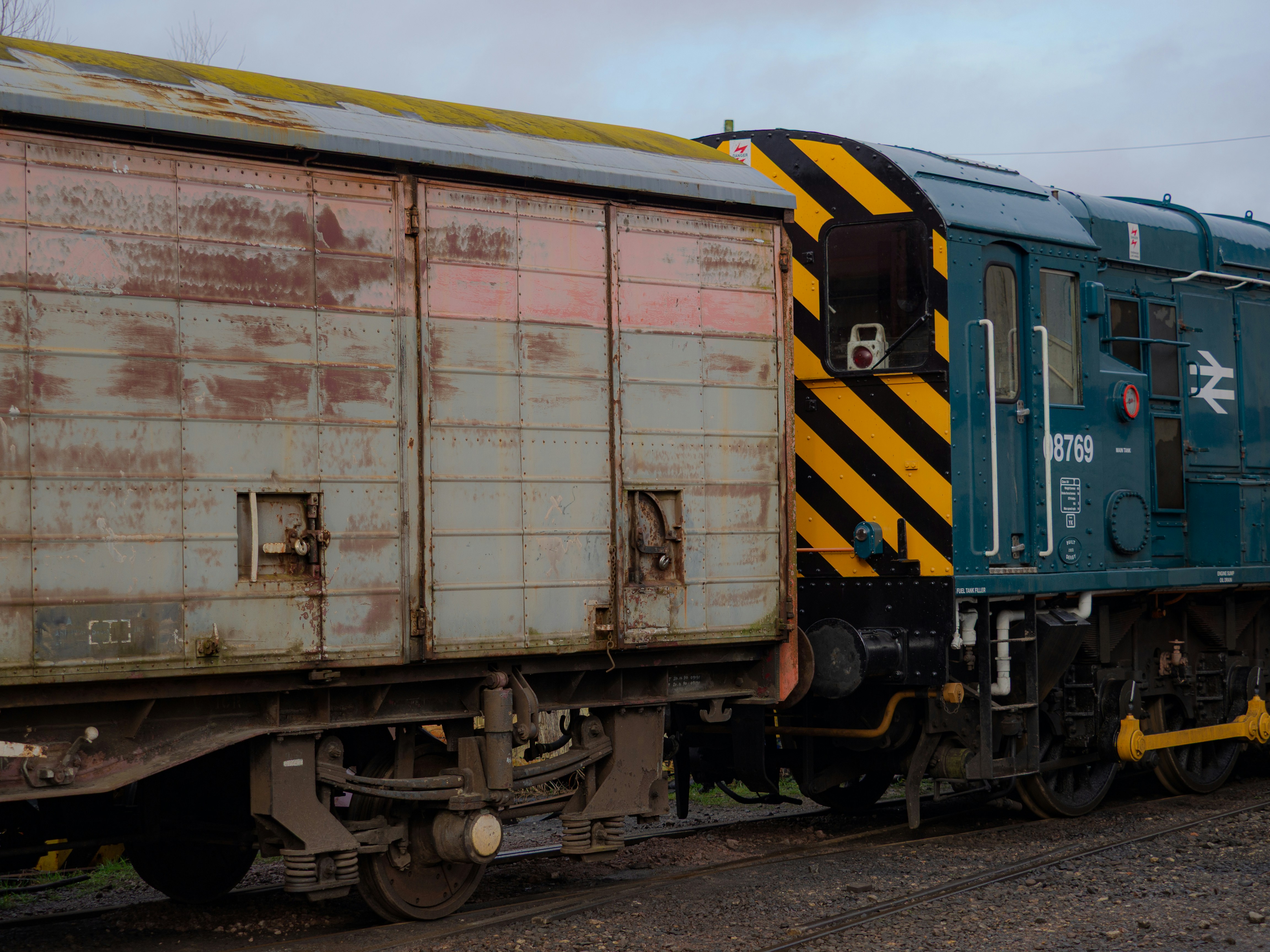 A blue train engine attached to a weathered freight car.