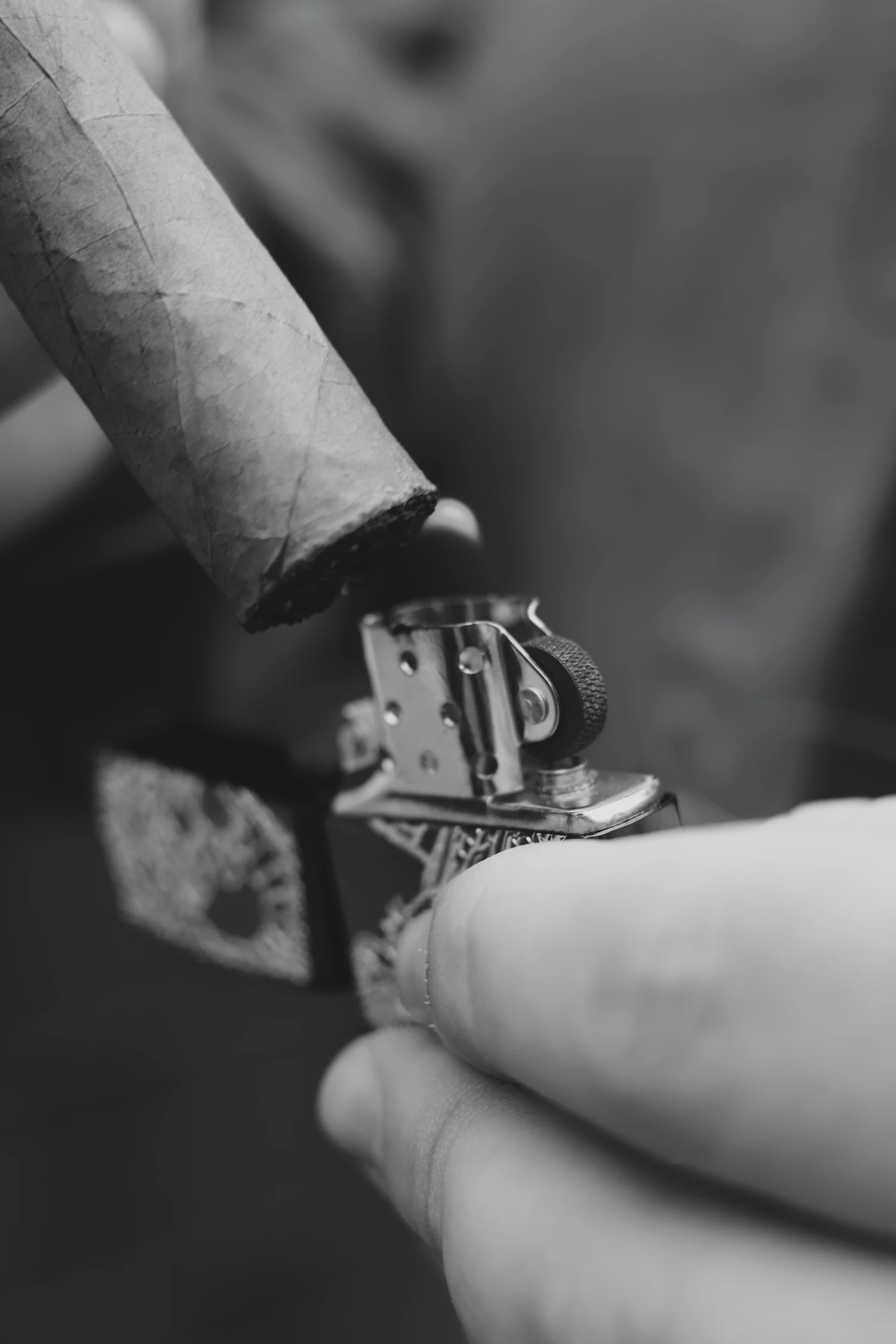 Close view of a cigar being carefully lit with a metal lighter