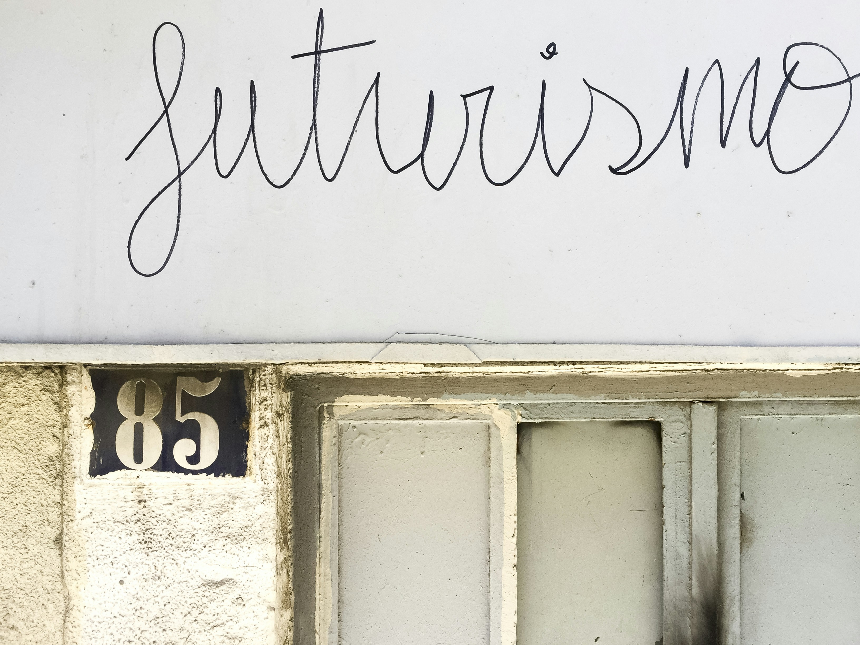 The word futurismo written on a wall above a window.