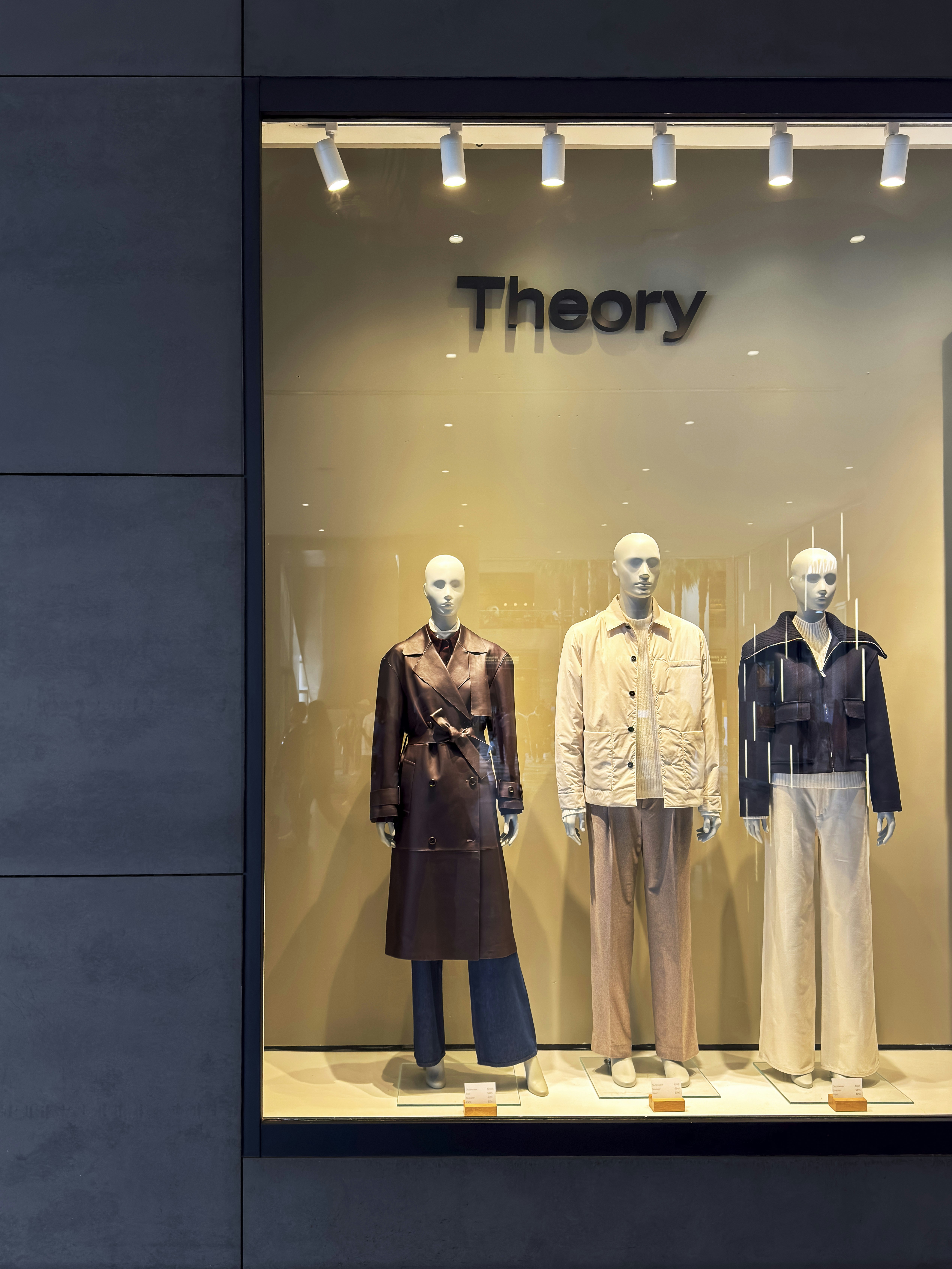 Three mannequins display clothing in a store window.