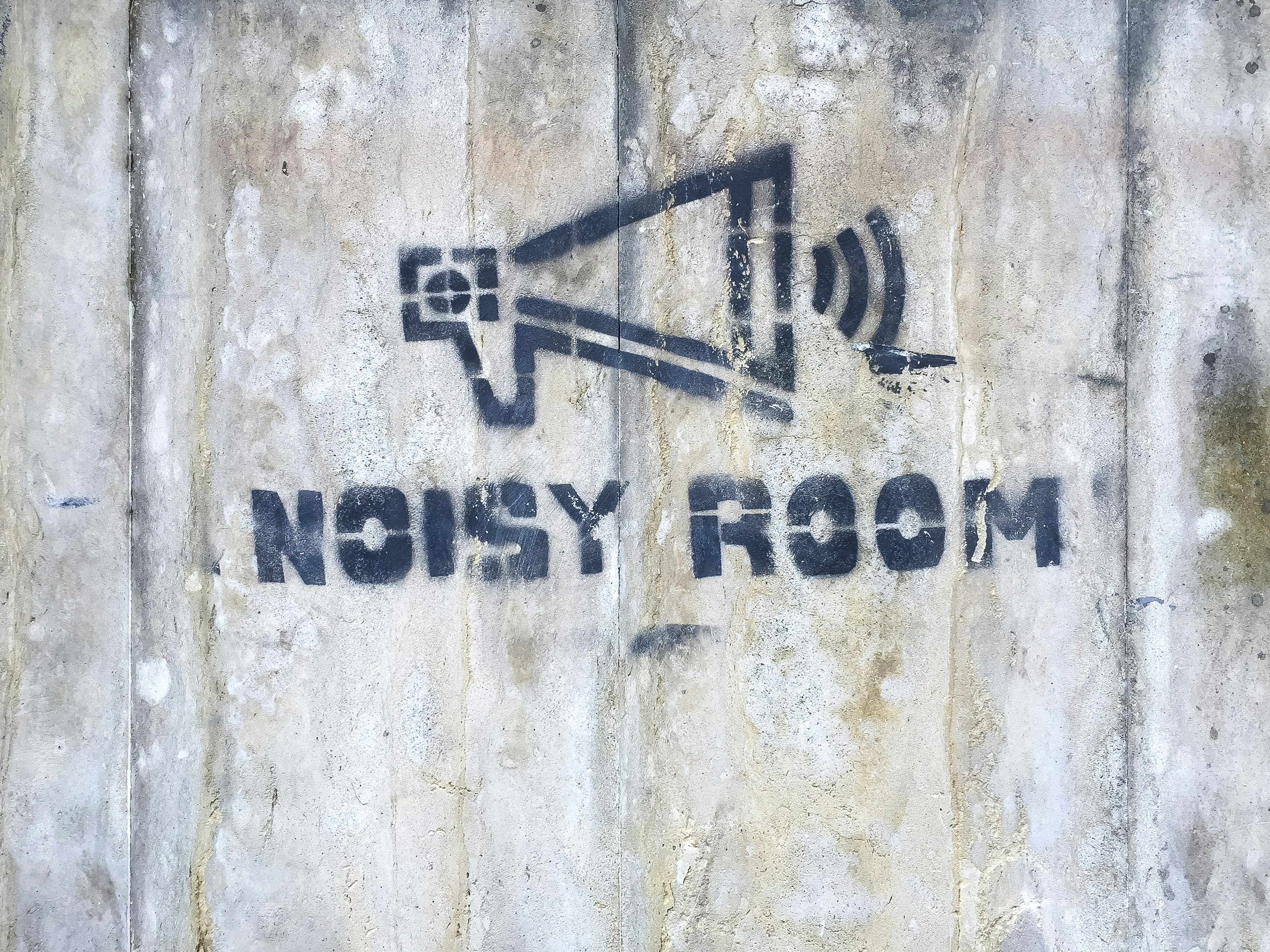 Noisy room sign spray-painted on concrete wall