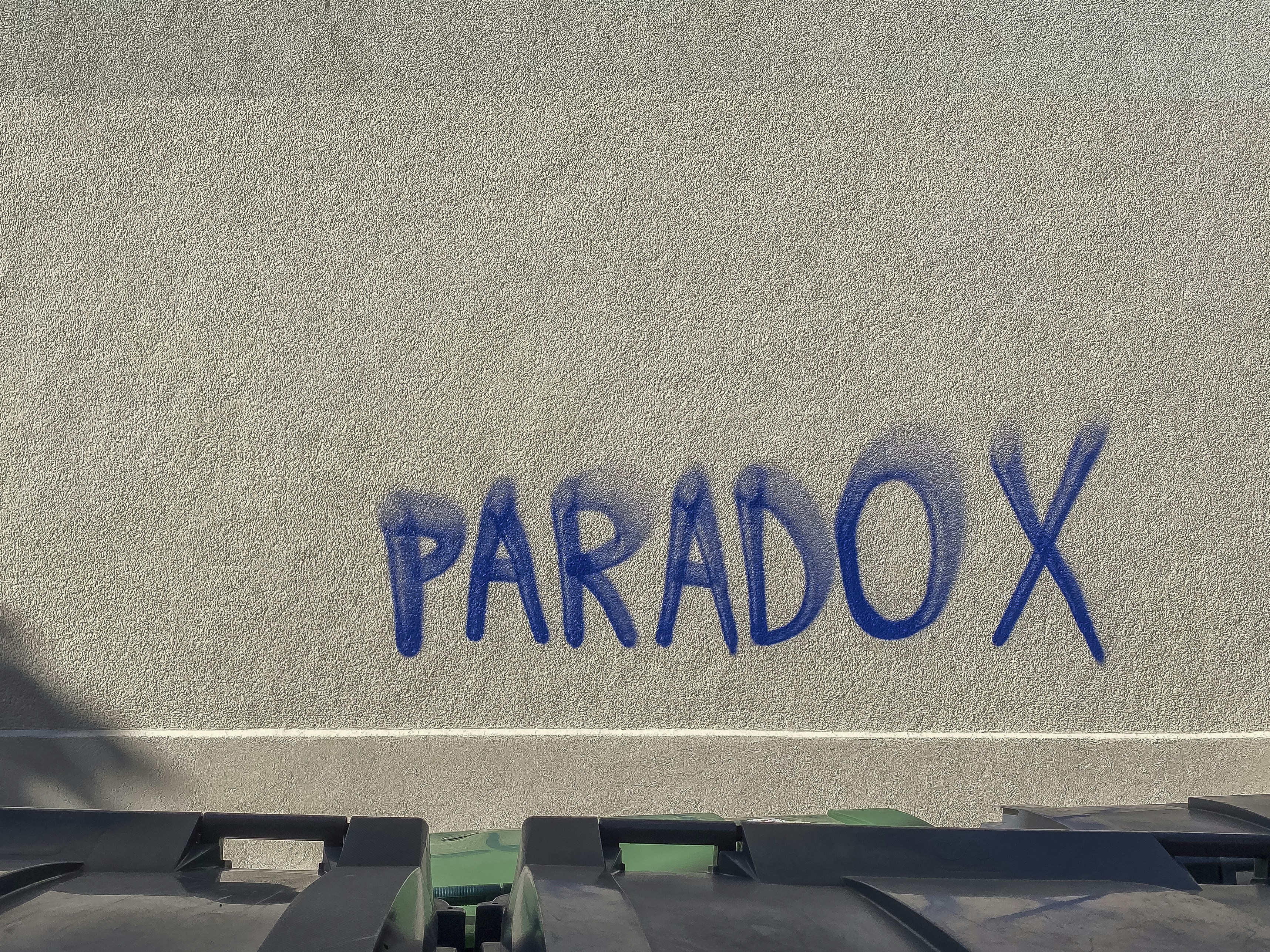 Blue graffiti spelling paradox on a wall.