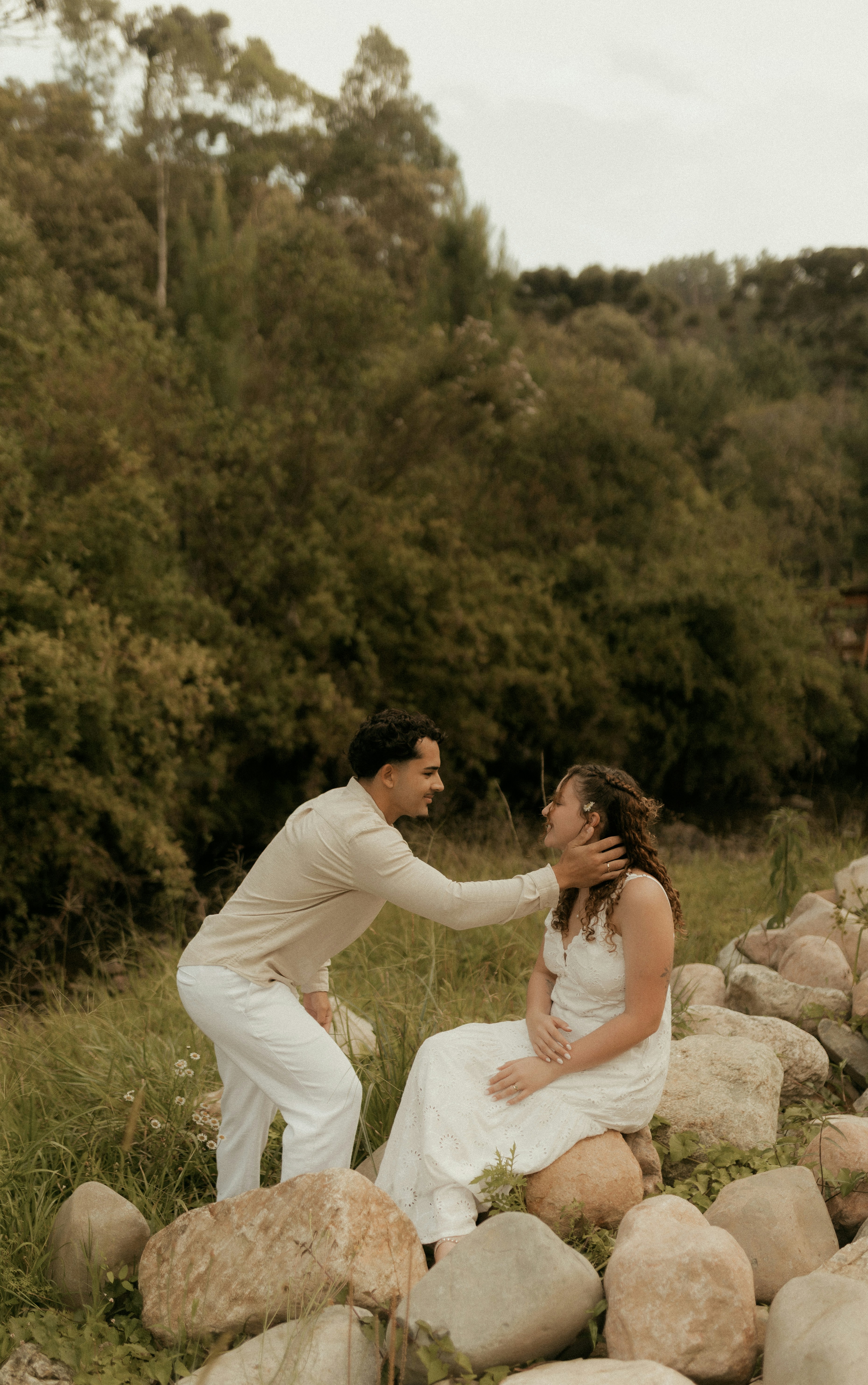 Couple s’enlaçant en plein air près de rochers et d’arbres