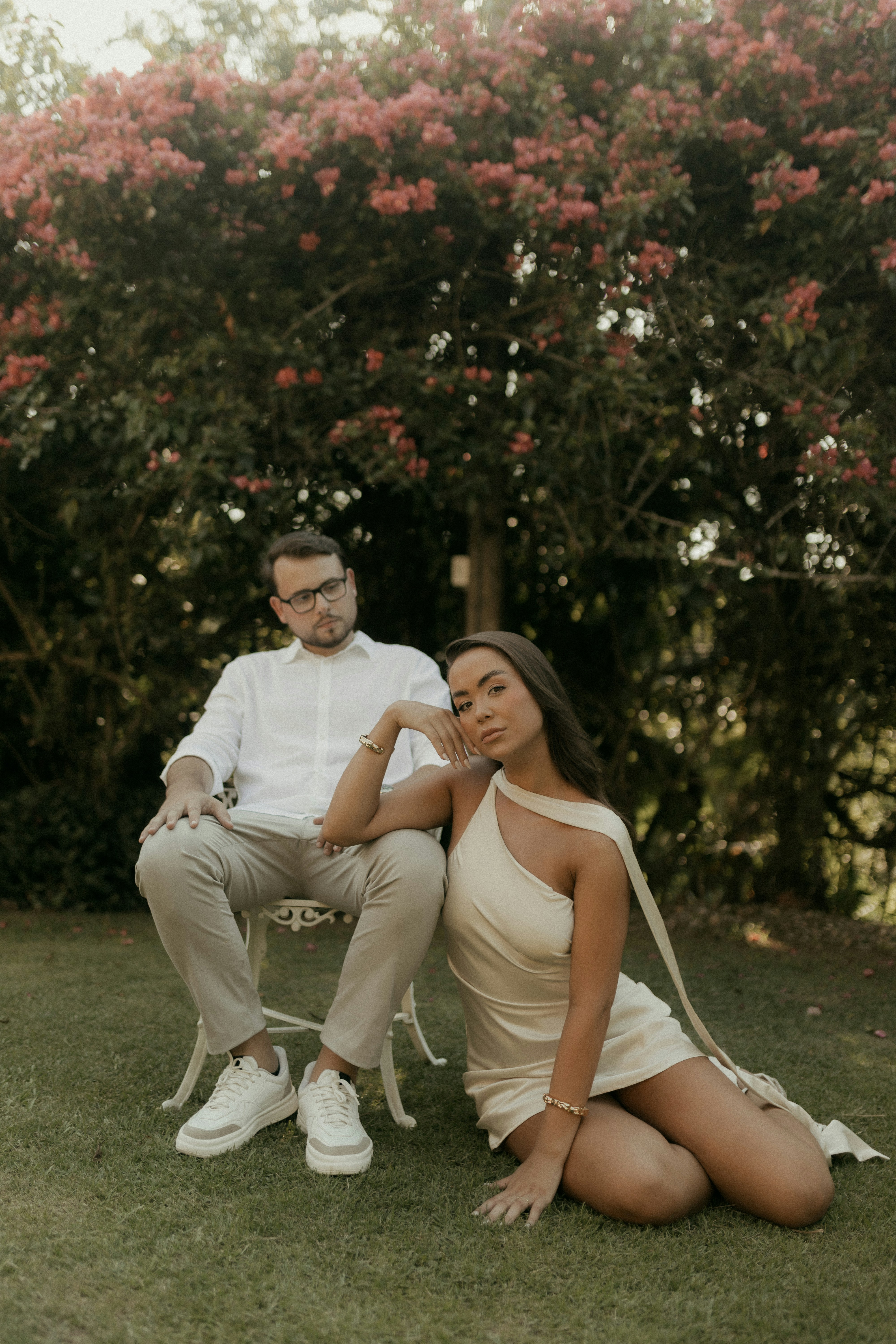 Un couple pose dehors près d’un arbre en fleurs.