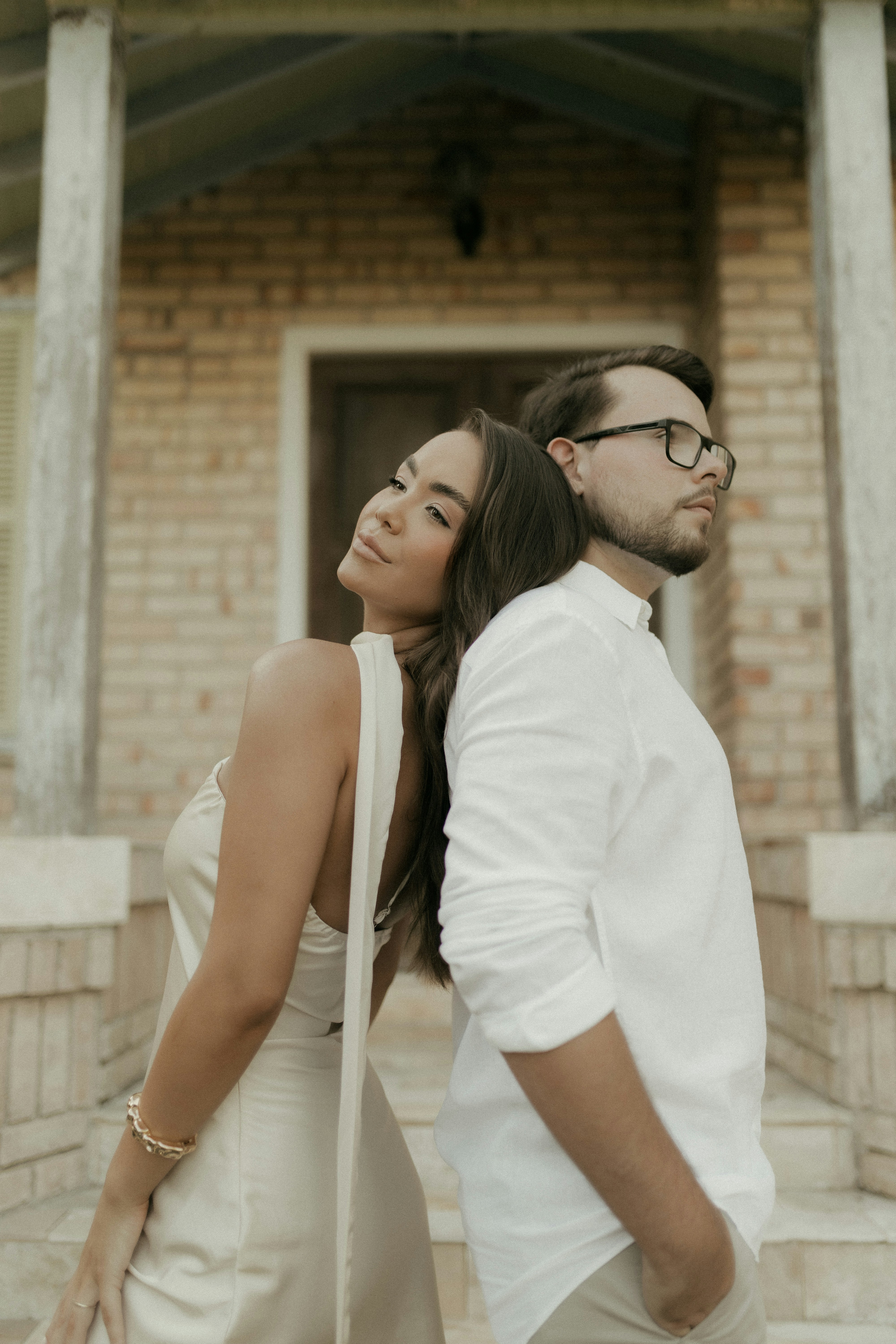 Couple adossé dos à dos devant un bâtiment en brique
