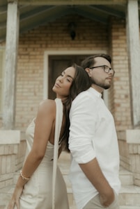 Couple leaning back-to-back in front of brick building