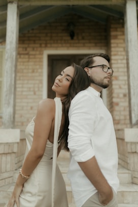 Couple leaning back-to-back in front of brick building
