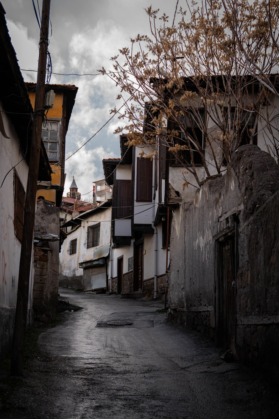 Narrow winding street lined with old buildings featuring white walls and brown roofs