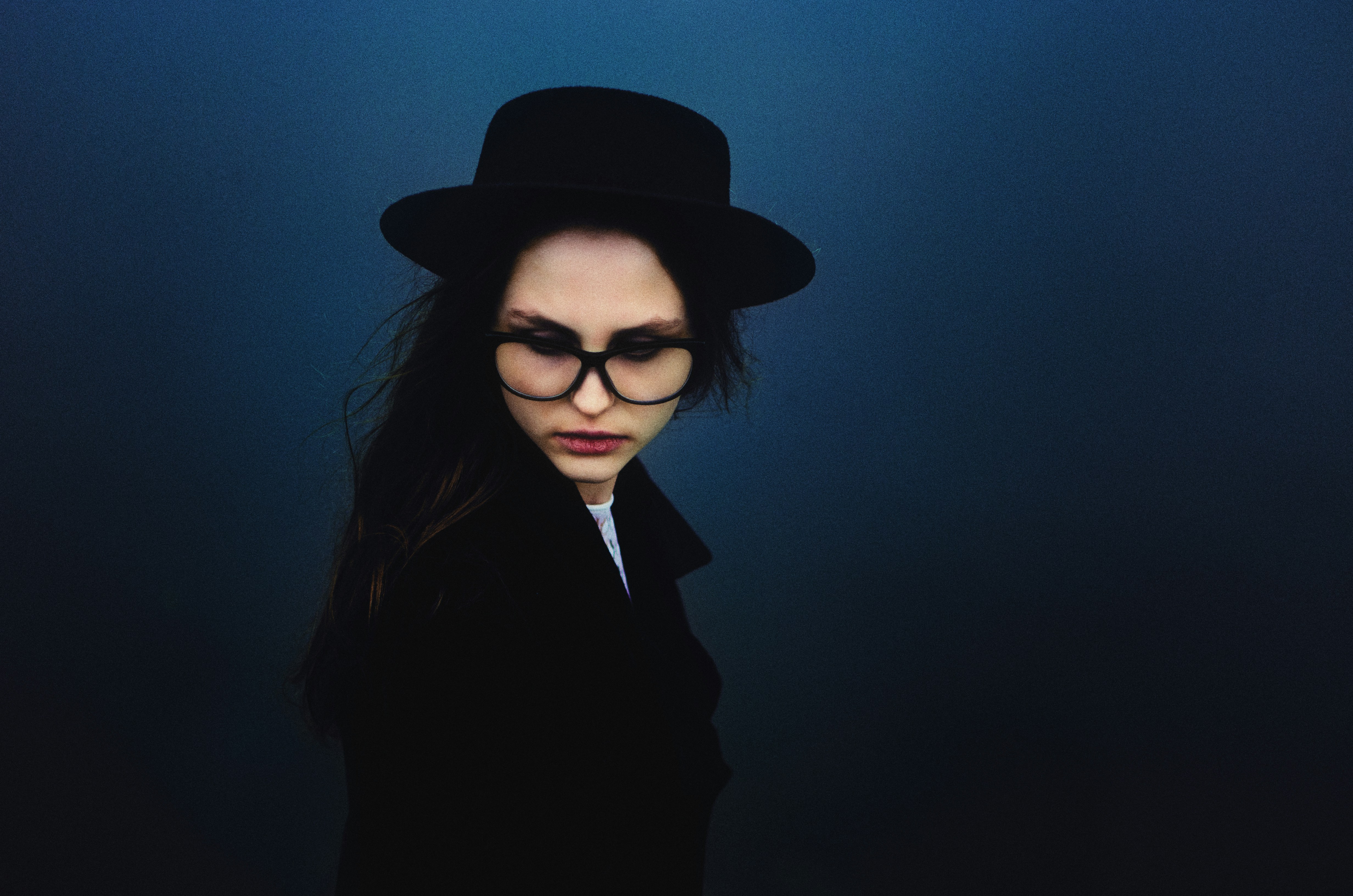 Femme au chapeau et aux lunettes sur fond sombre
