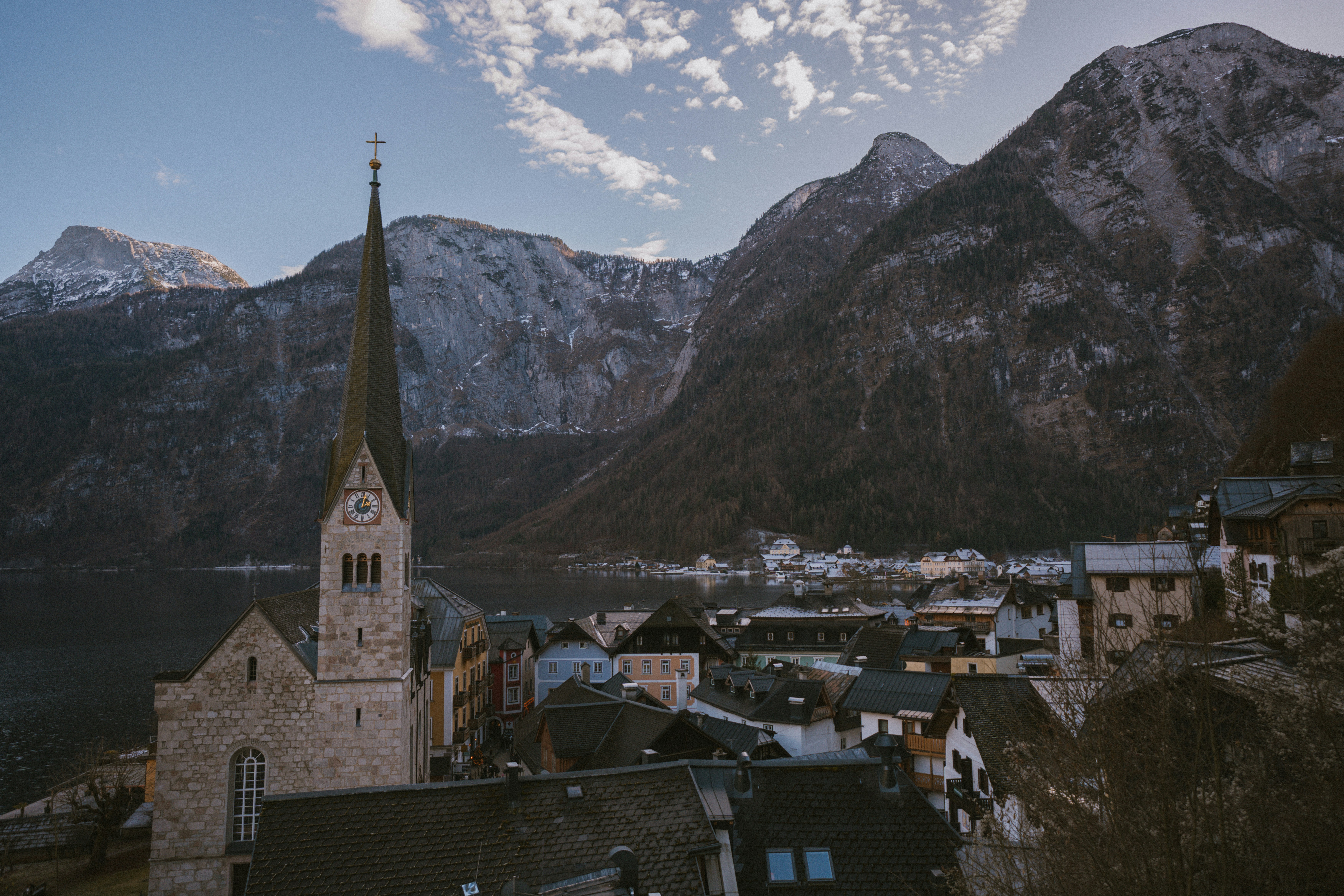 Village with church steeple by lake and mountains
