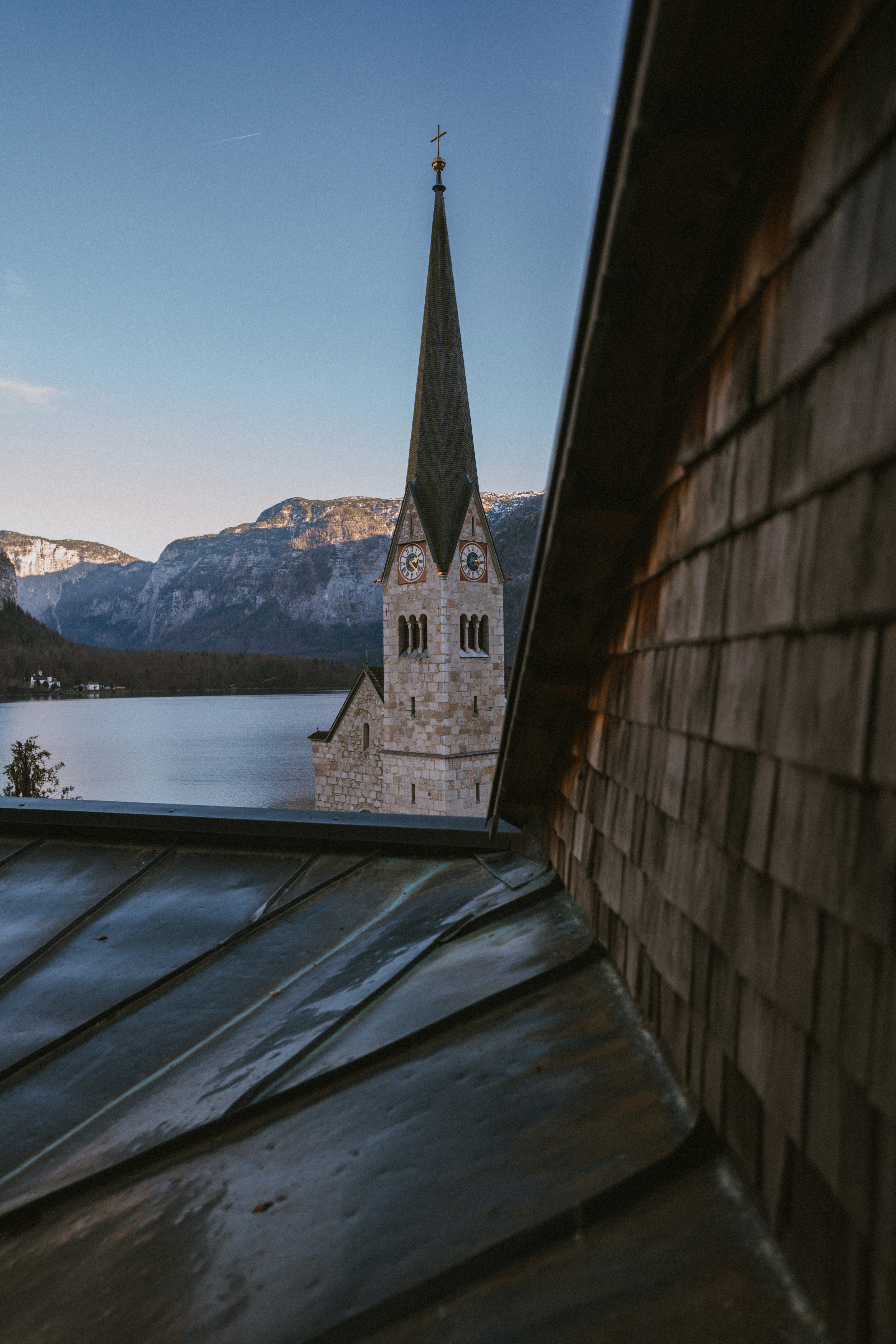 Church steeple rises above a serene lake and mountains.