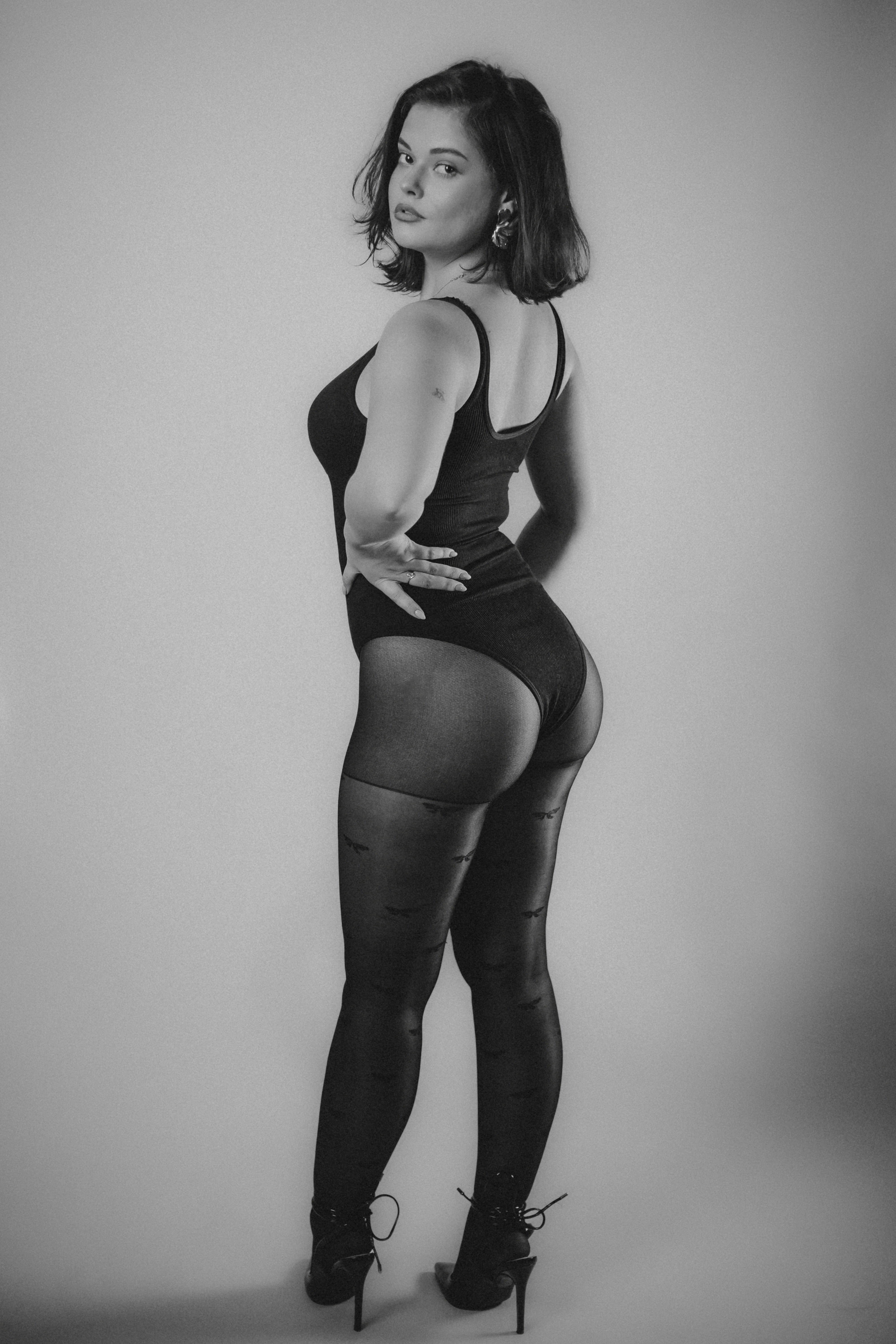 Woman in black bodysuit and stockings posing