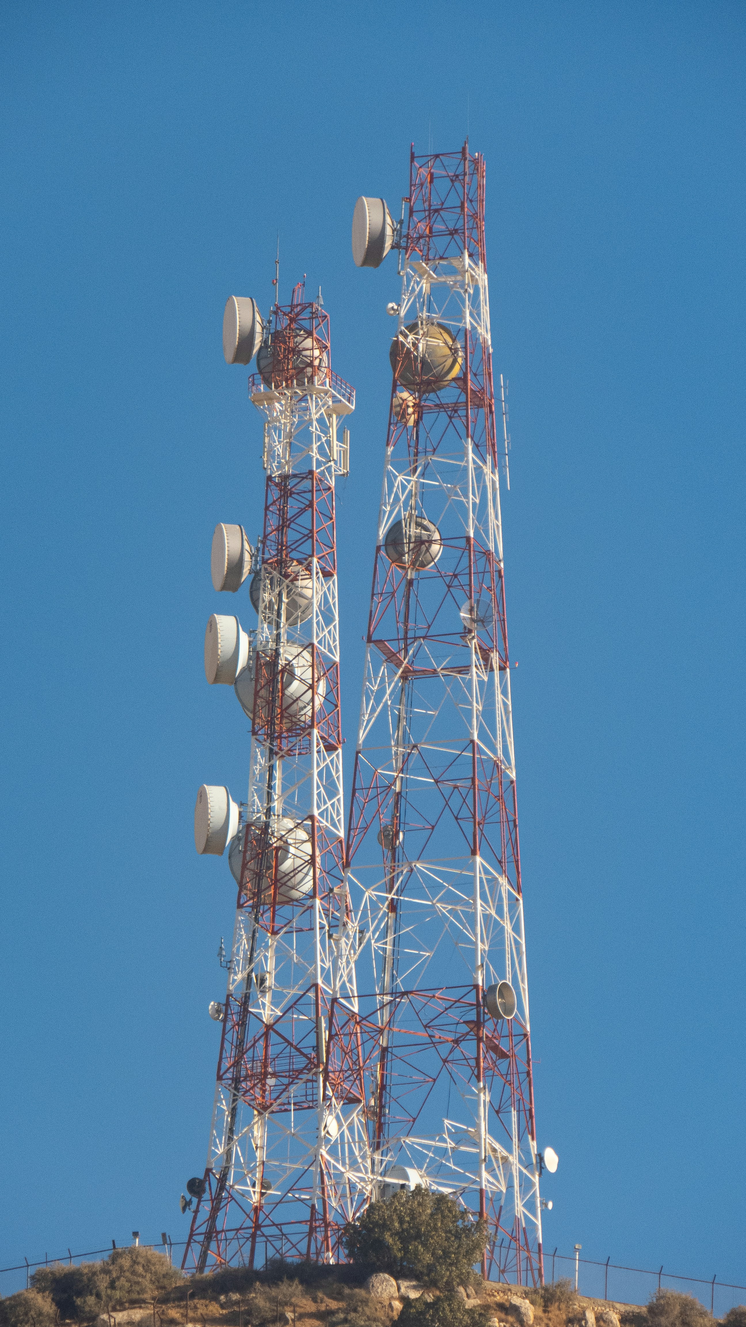 Two tall communication towers against a clear blue sky.