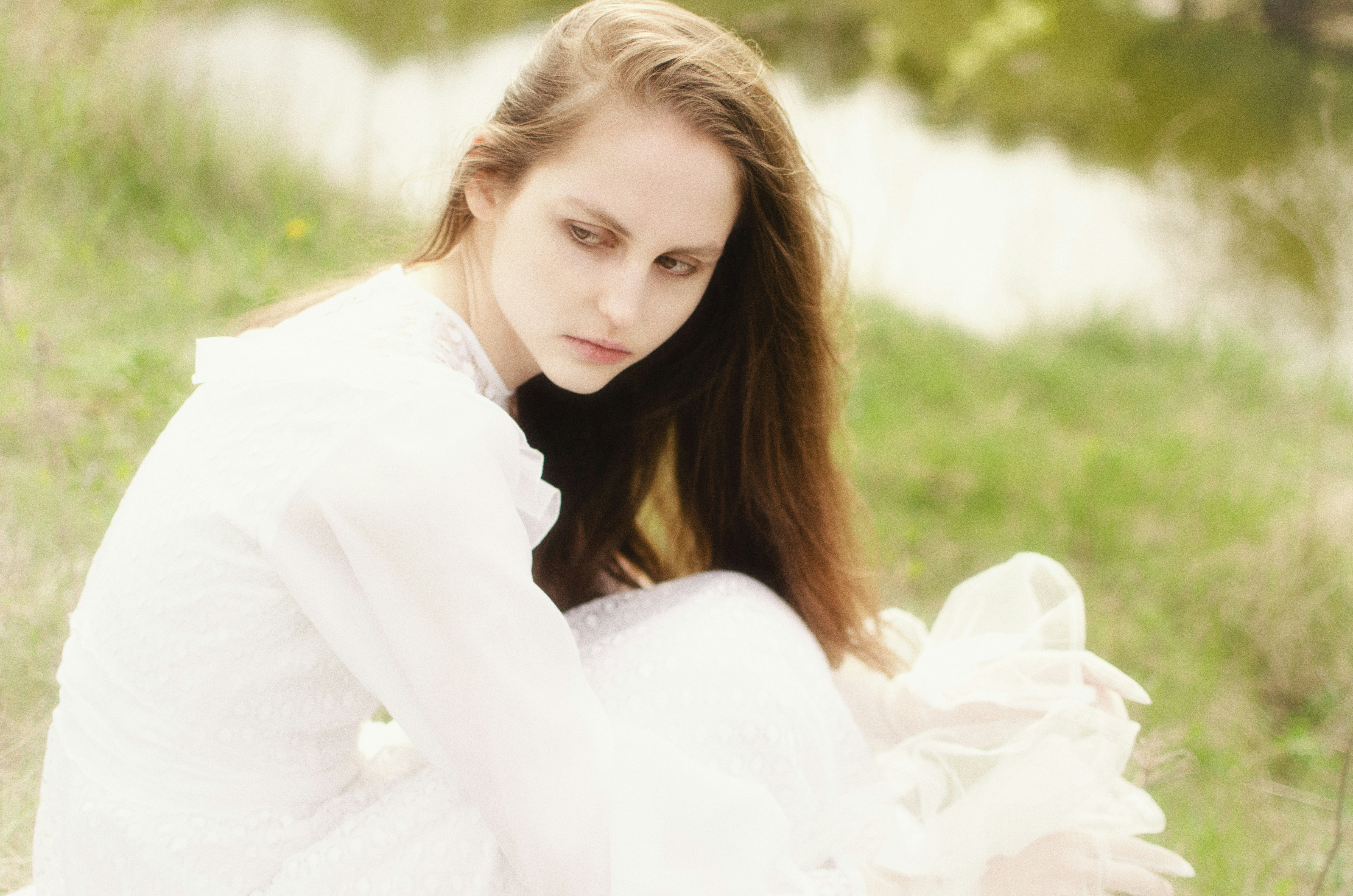 Jeune femme en robe blanche assise dans un champ