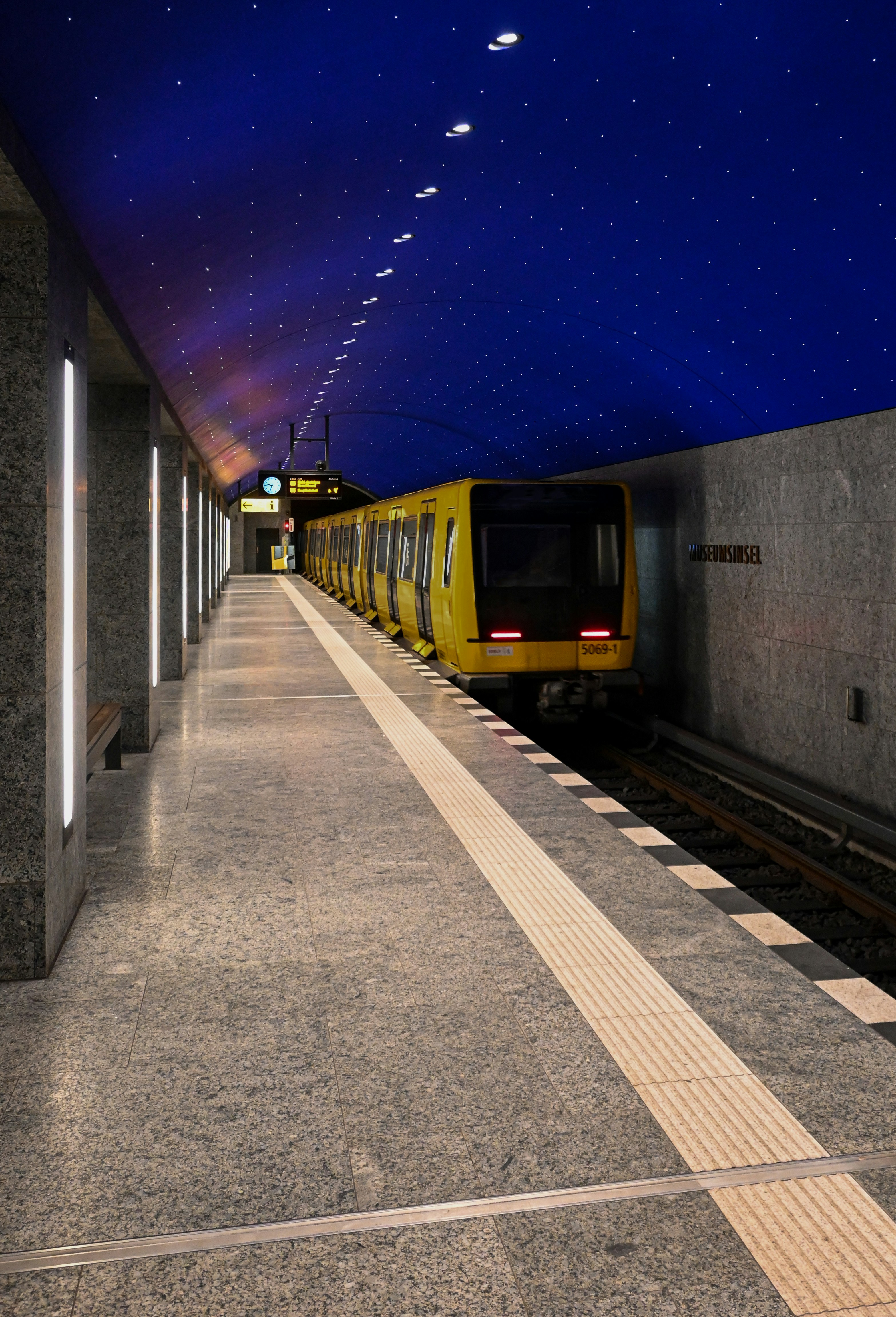 A yellow train waits at a subway station platform.