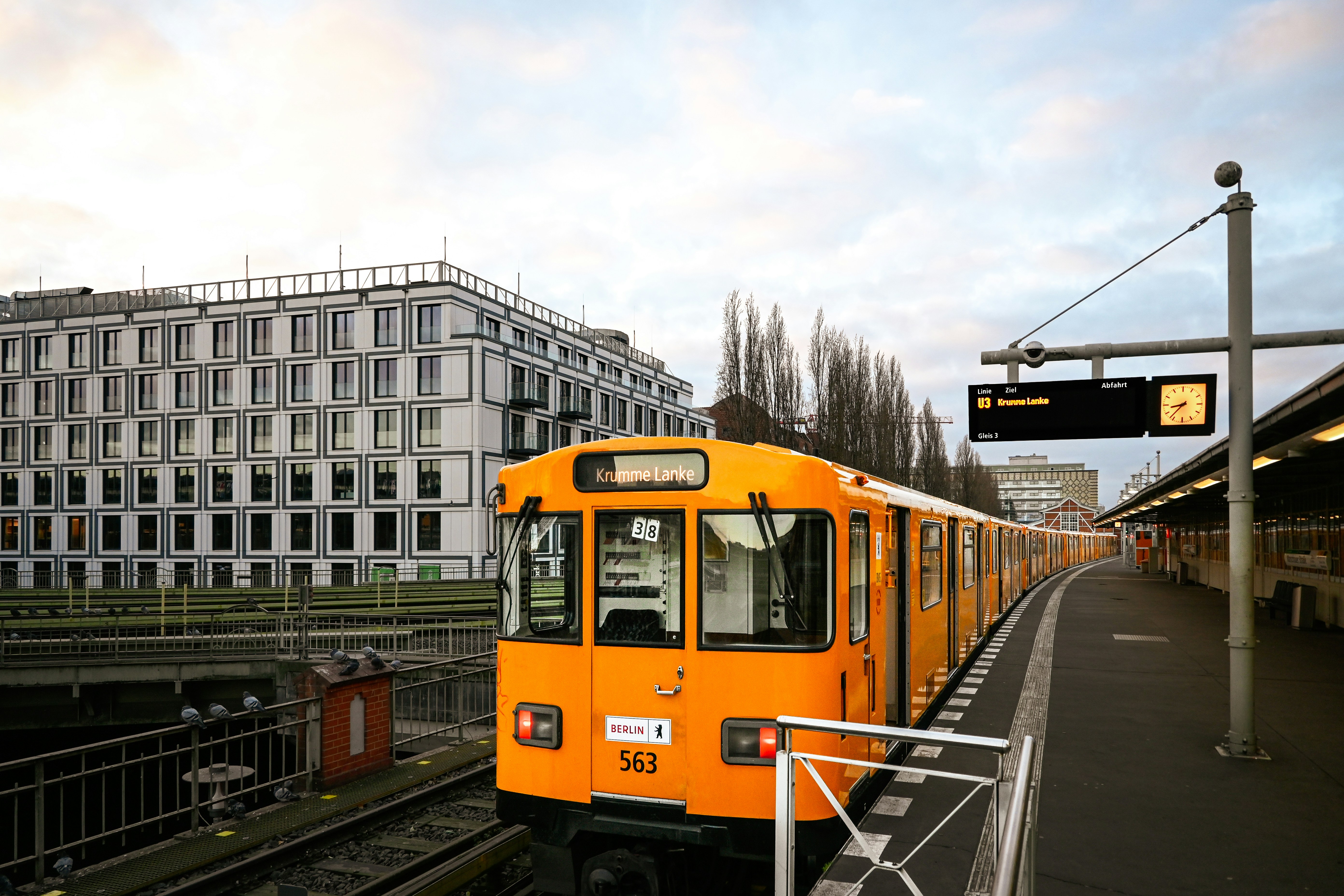 An orange train at a station platform.