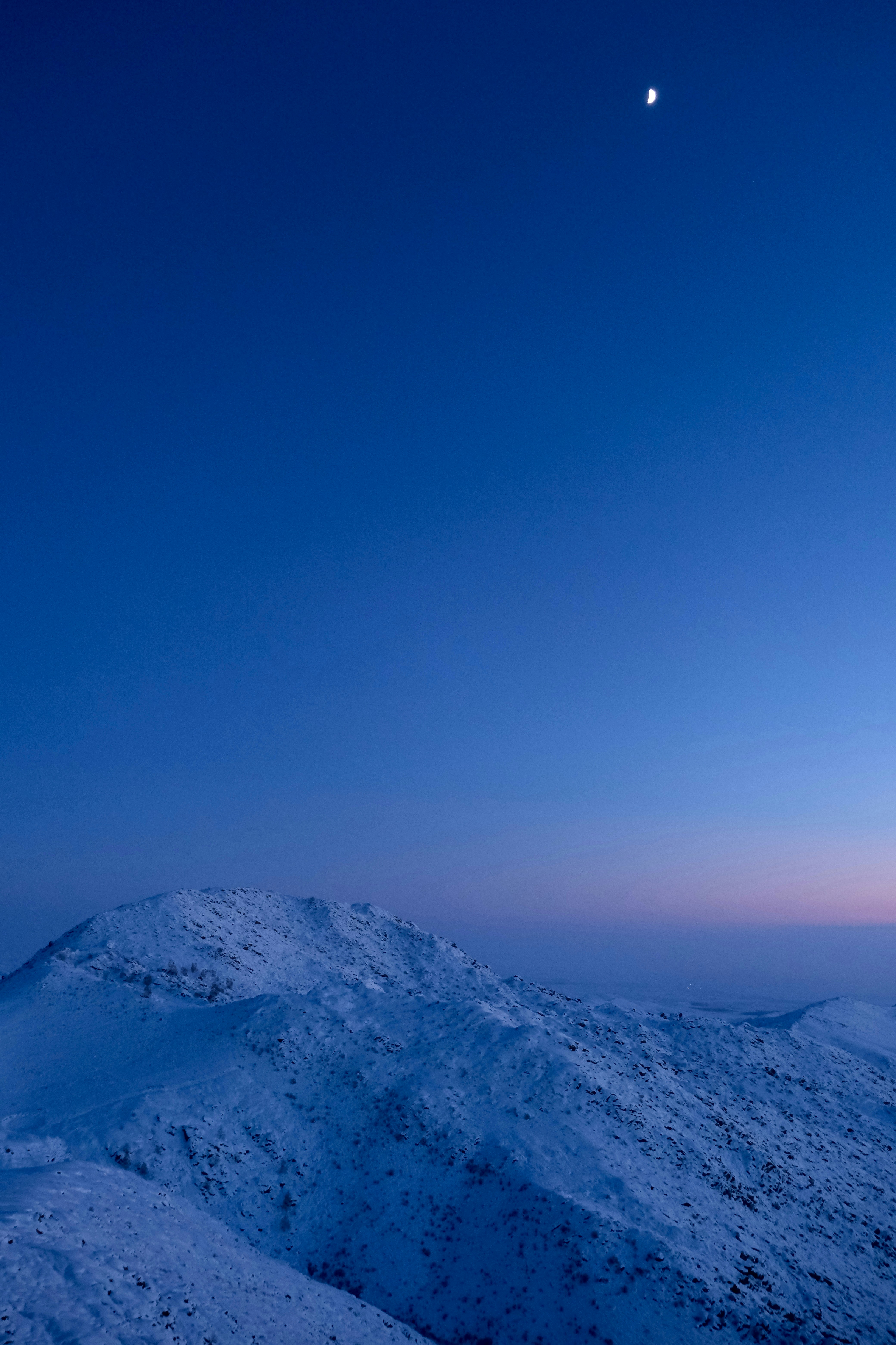 Cadena montañosa nevada bajo un cielo azul profundo al crepúsculo.