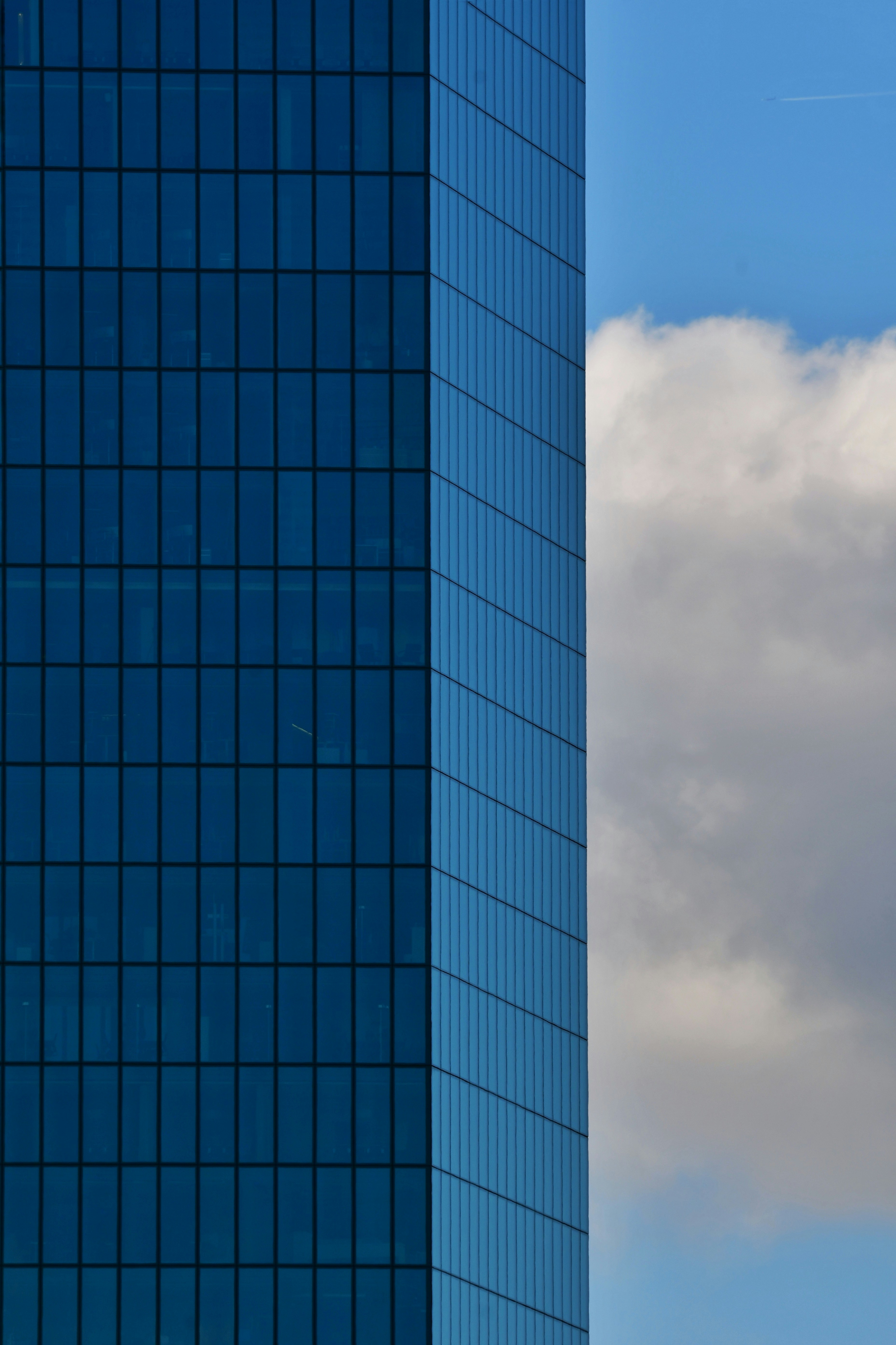 Modern blue glass skyscraper against a cloudy sky