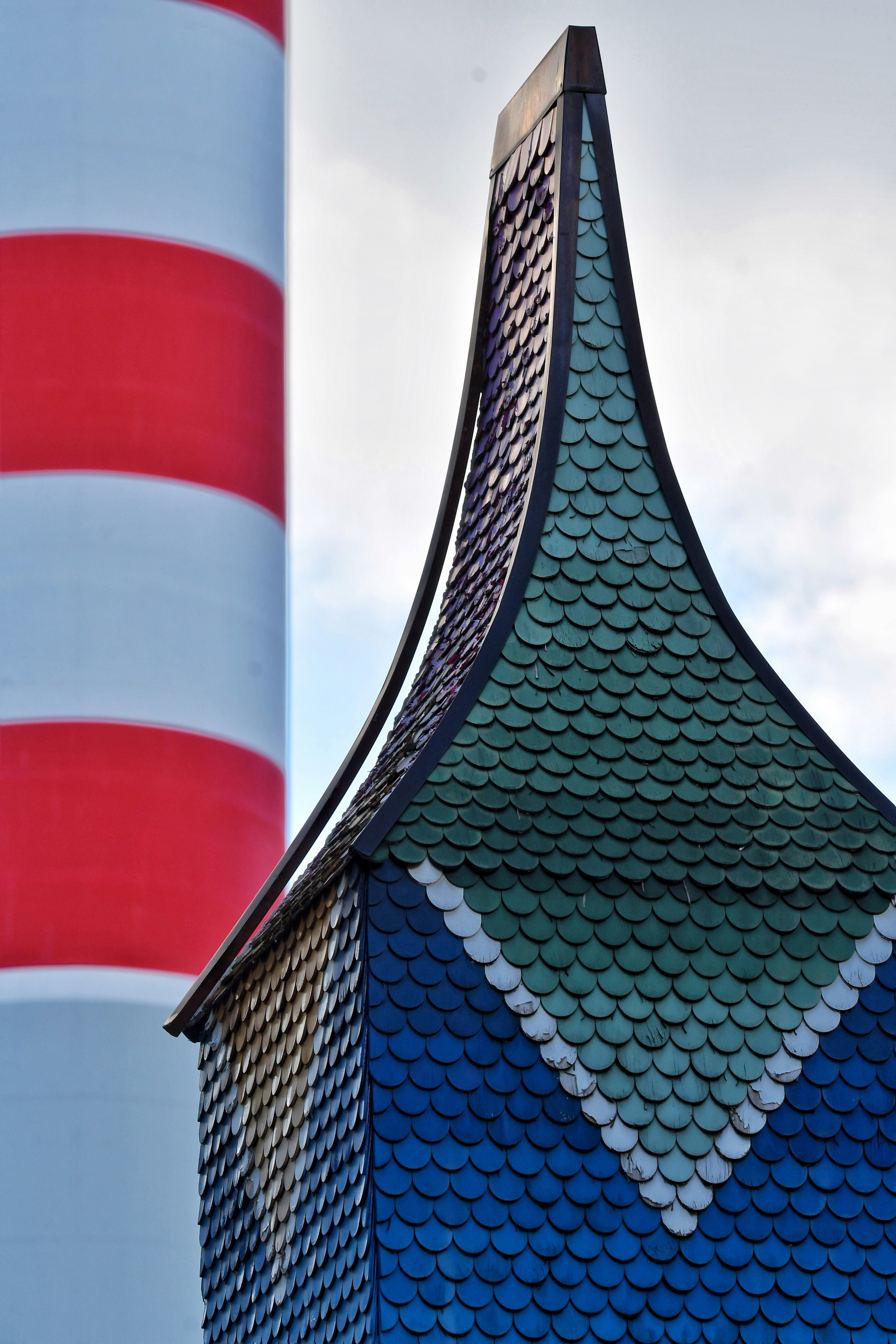 Red and white striped tower next to colorful tiled building