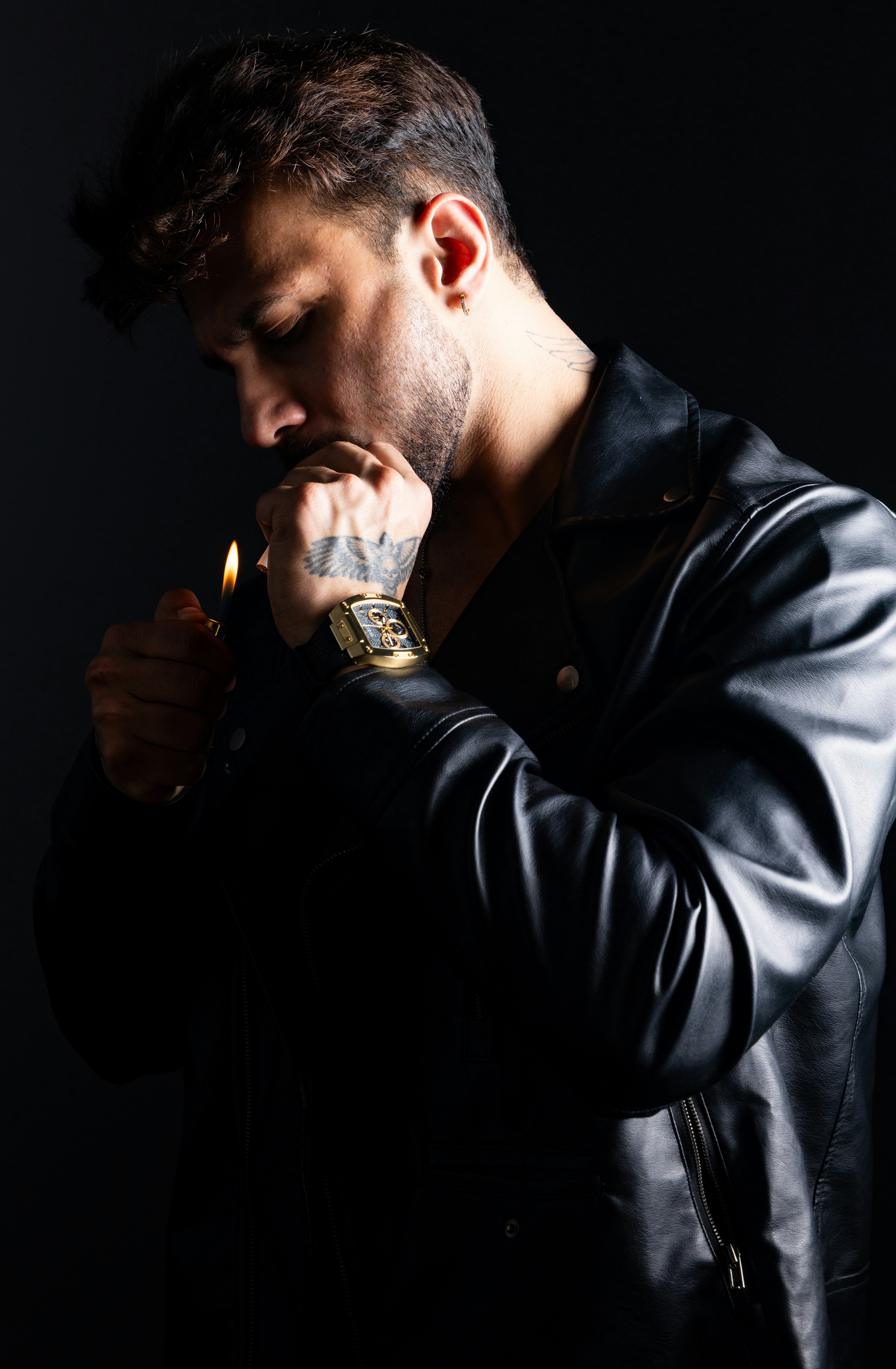 Man in leather jacket lighting cigarette with a lighter.