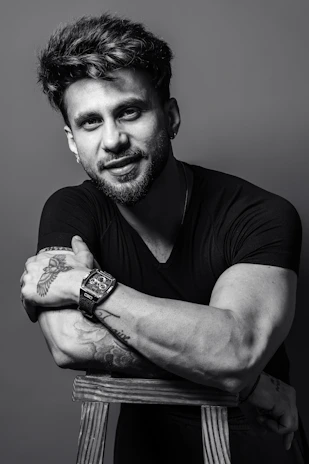 Man with tattoos and watch leaning on chair