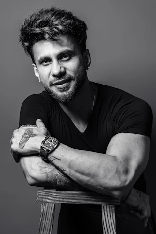 Man with tattoos and watch leaning on chair