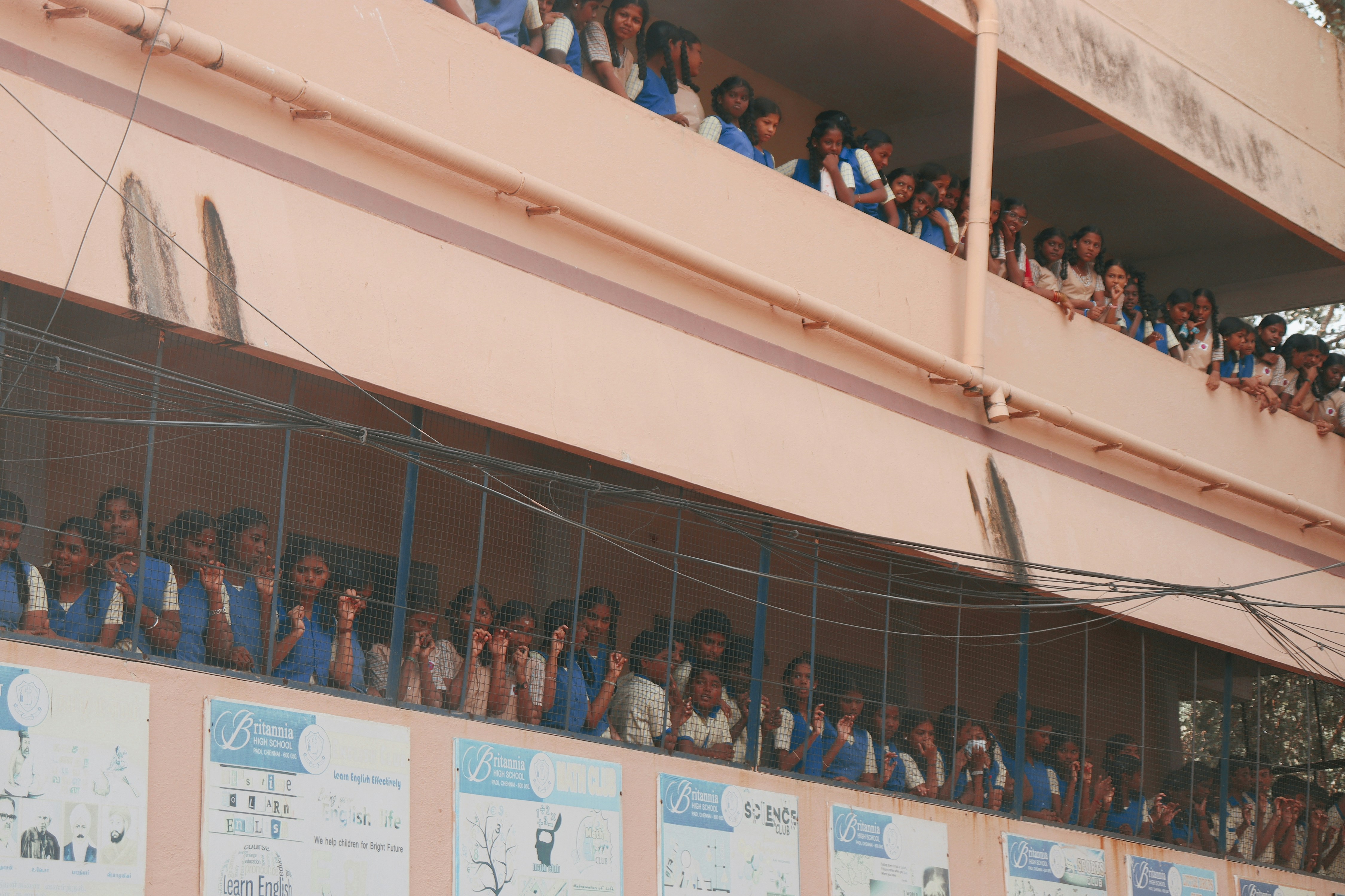 Students in school uniforms looking out from balconies.