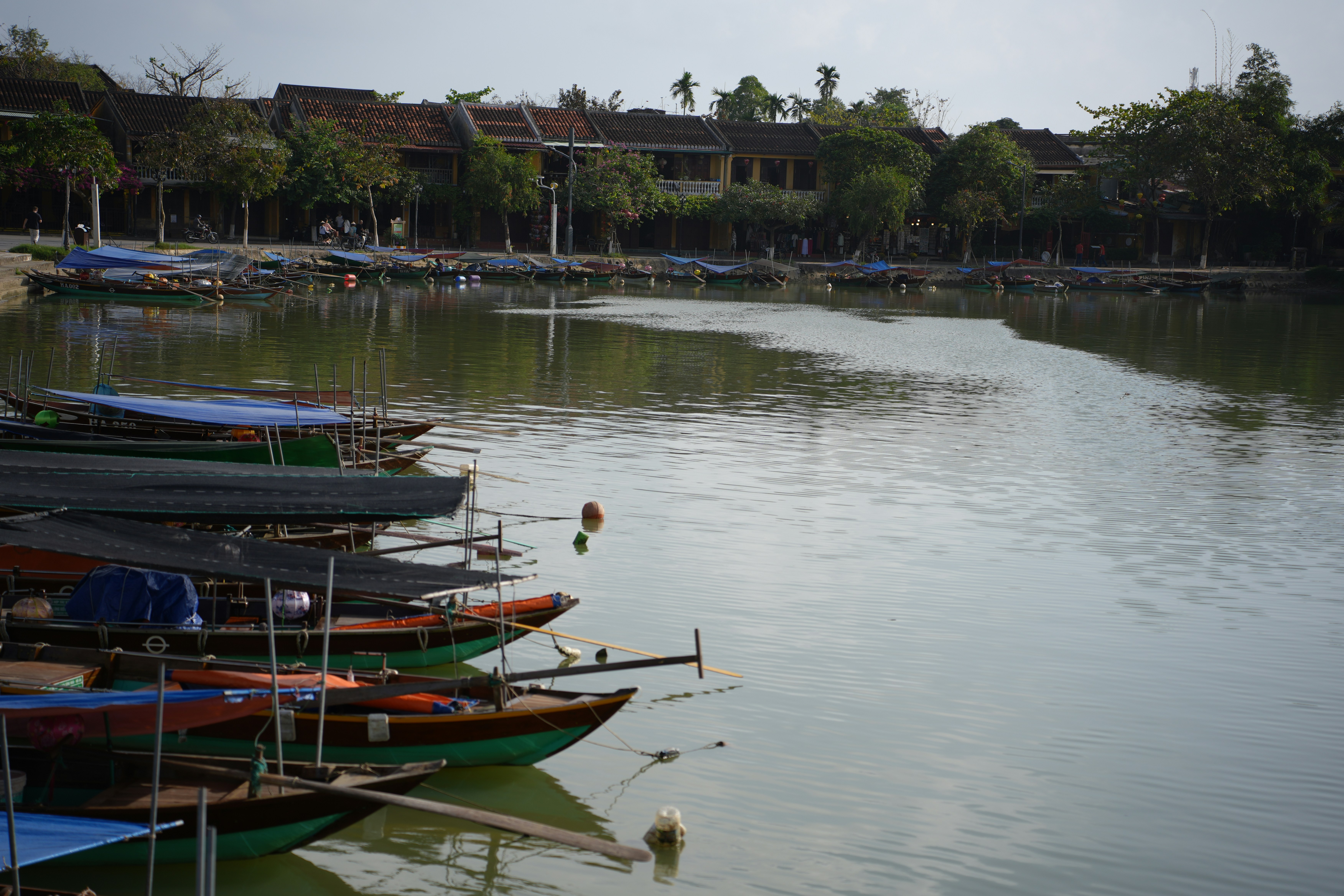 Boats docked on a calm river with buildings in background