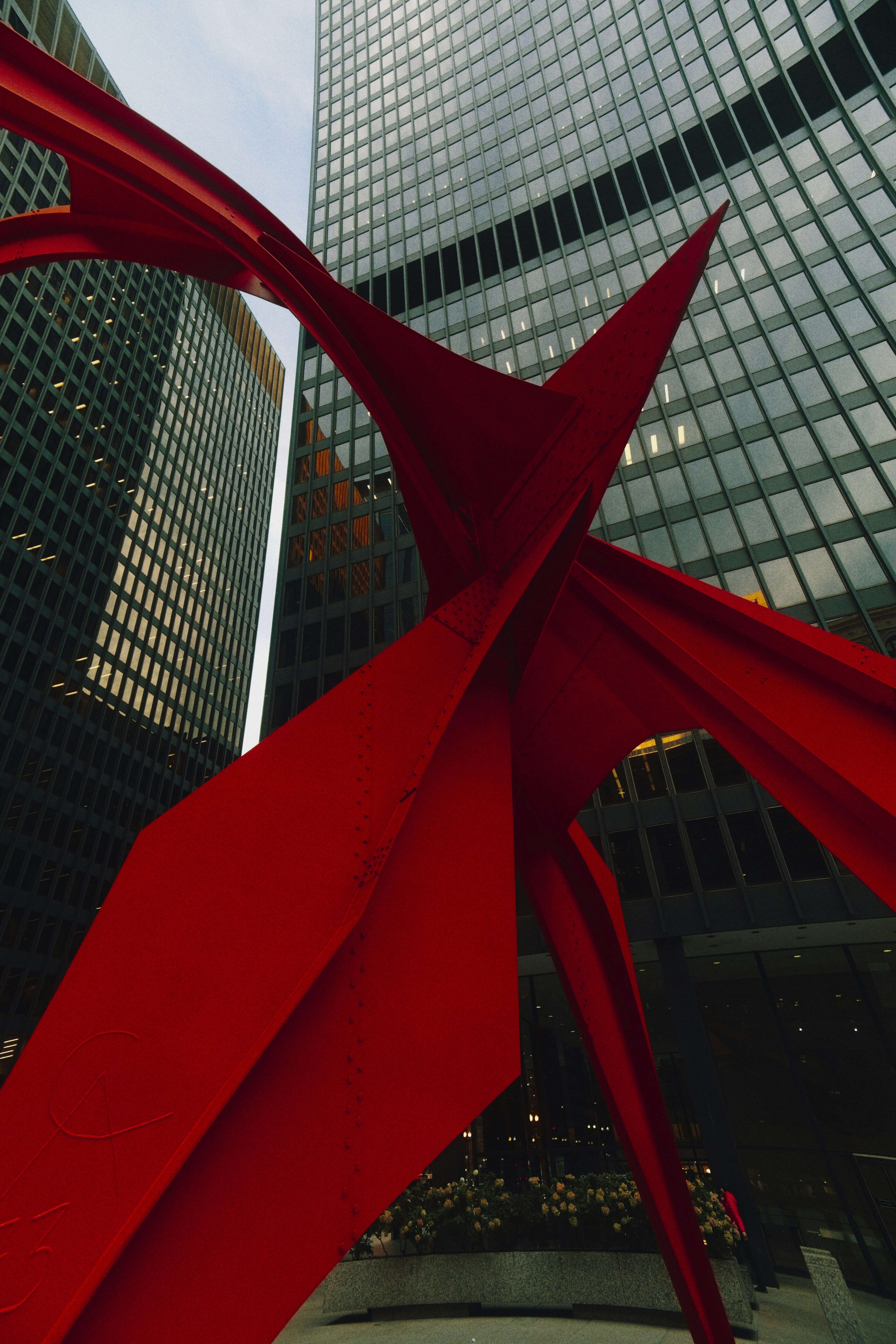 Red abstract sculpture in front of modern buildings