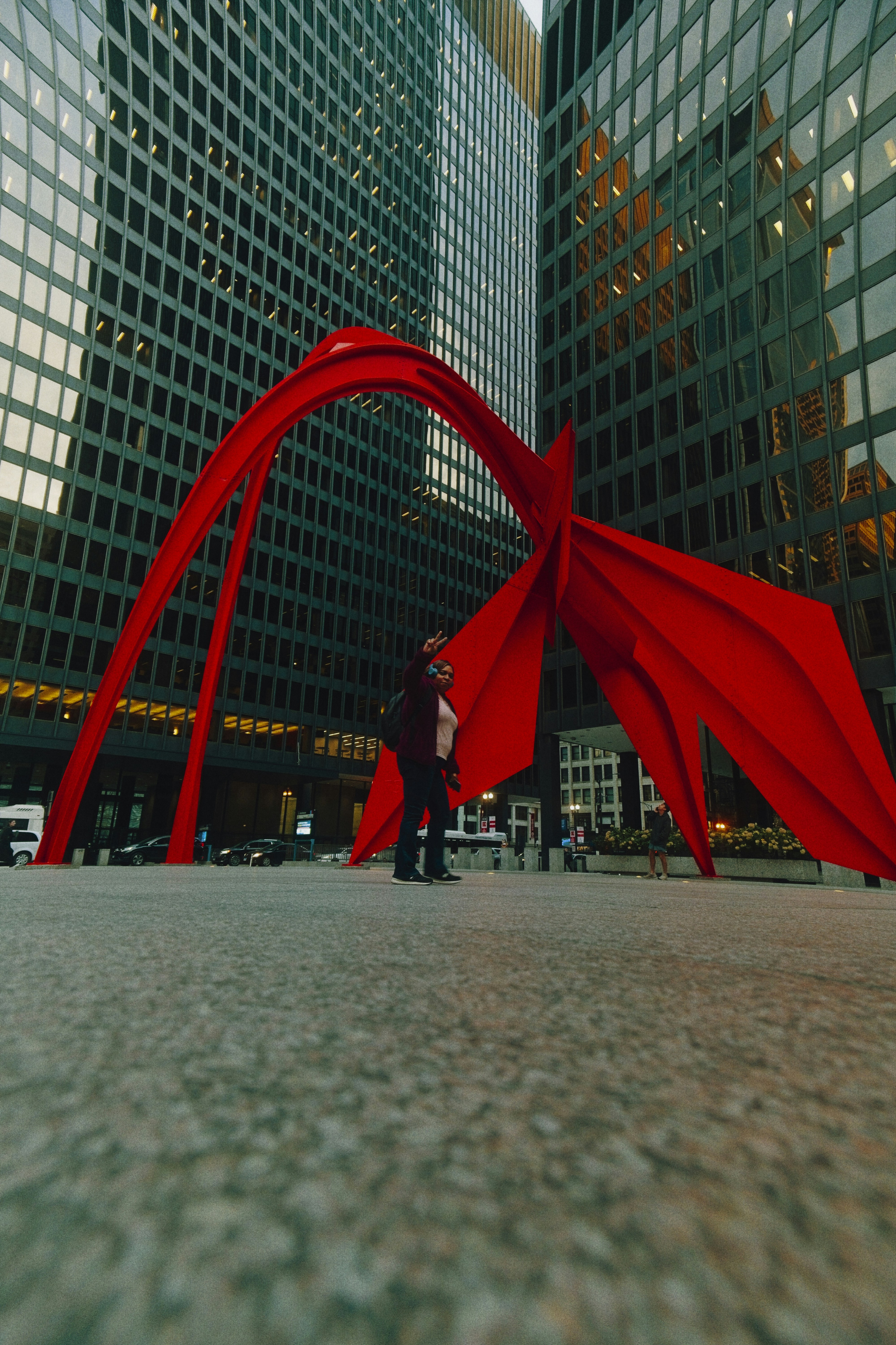 People stand near a large red abstract sculpture downtown.