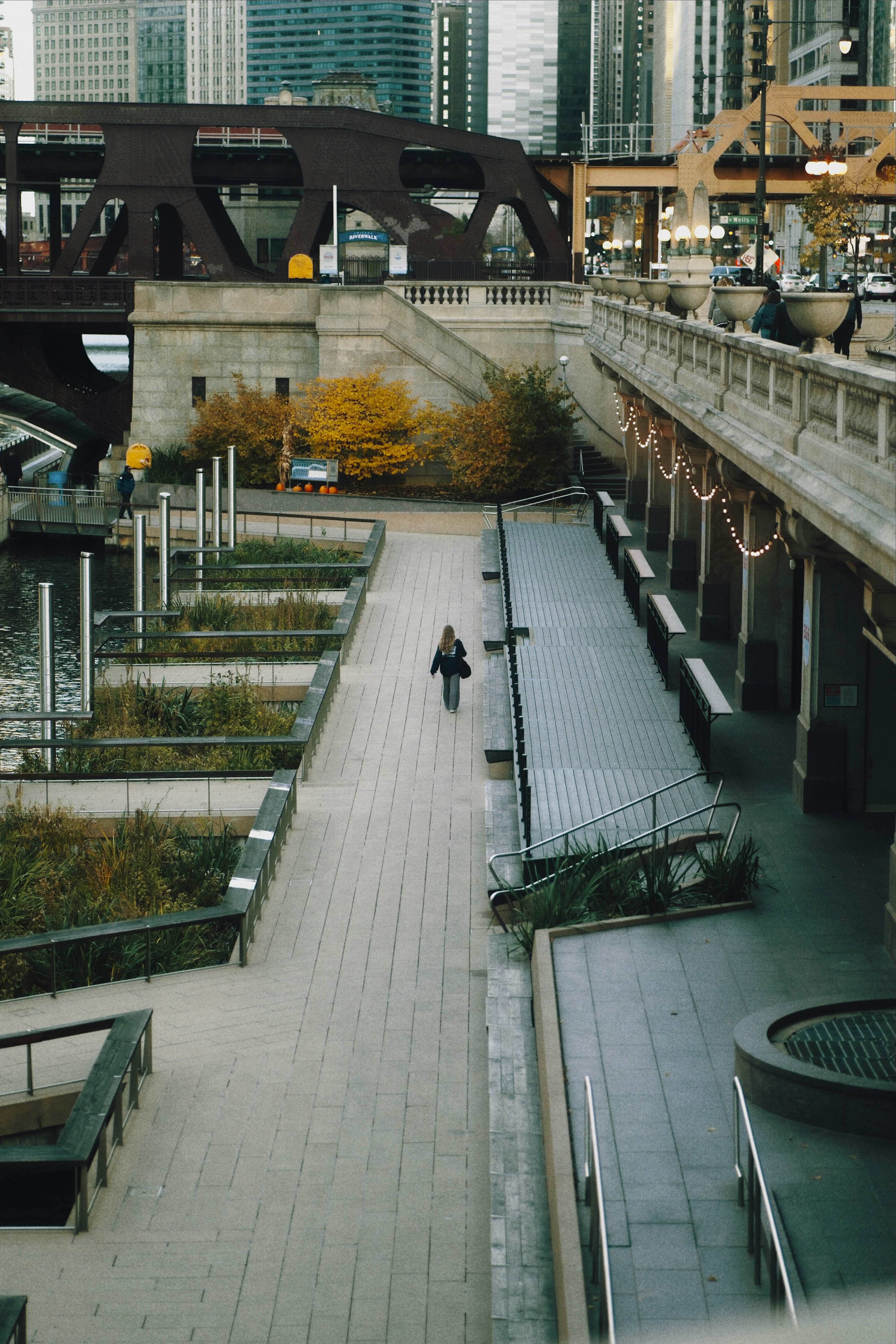 A person walks along a city riverfront promenade.