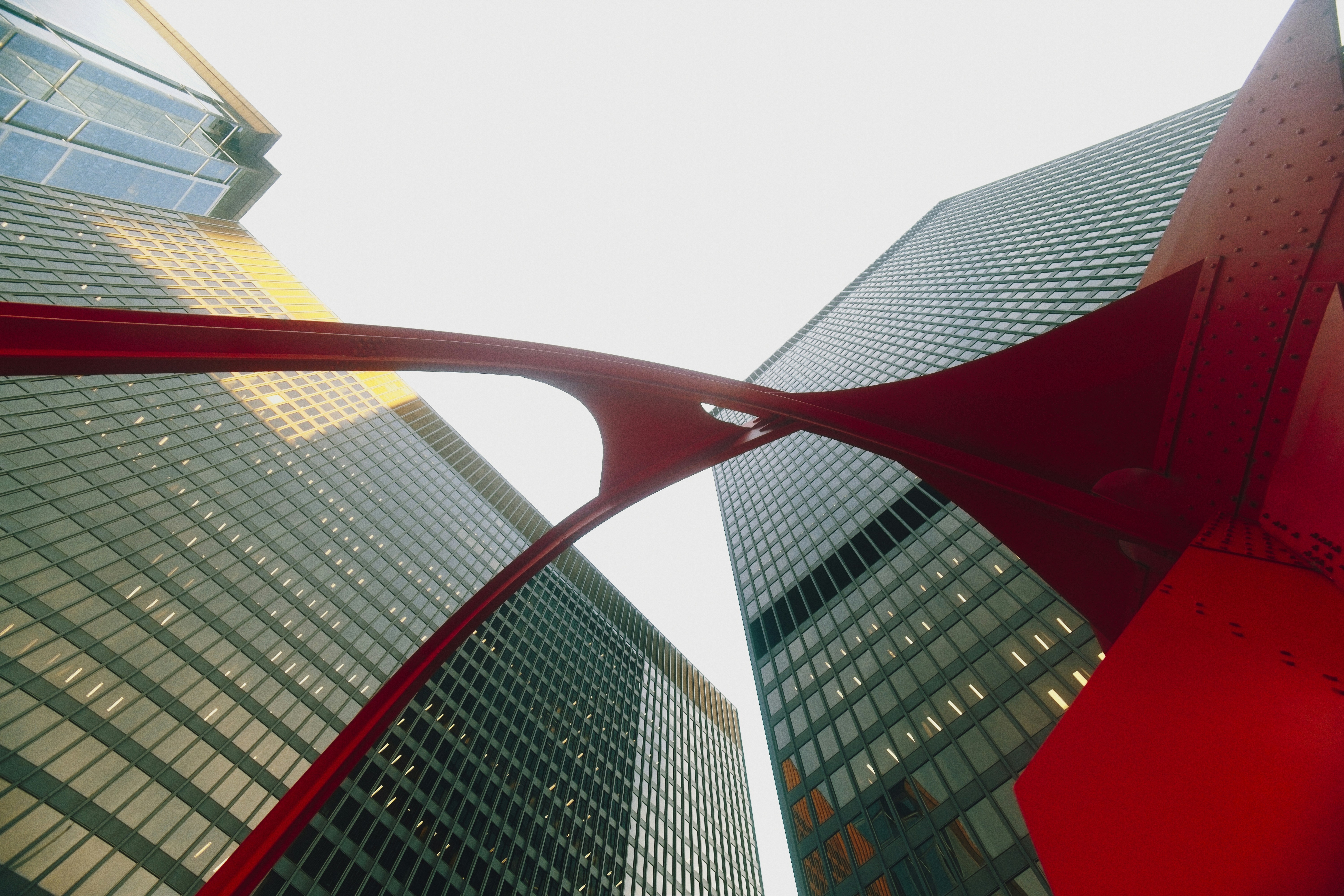 Modern red sculpture against tall glass buildings