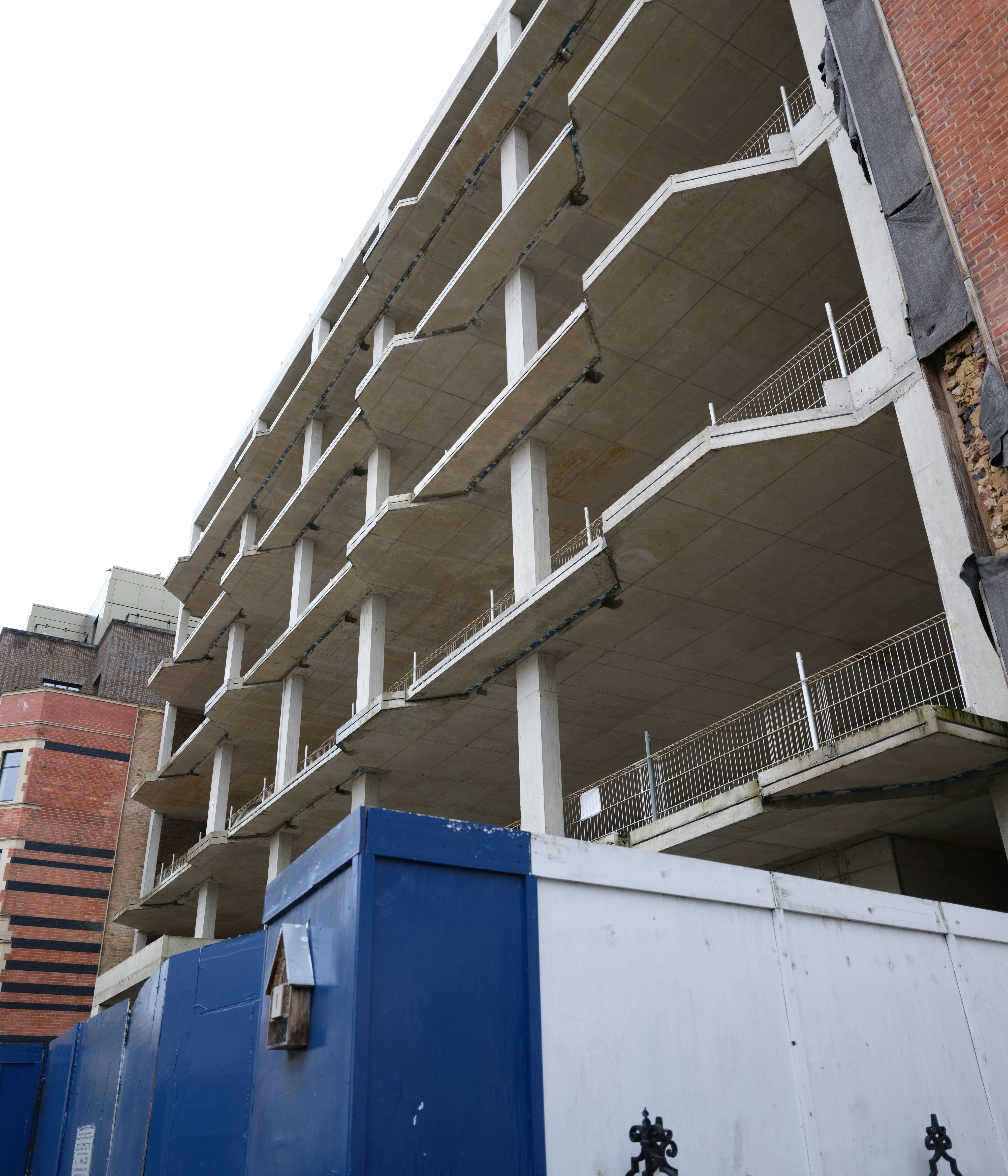 Concrete building under construction with blue barrier