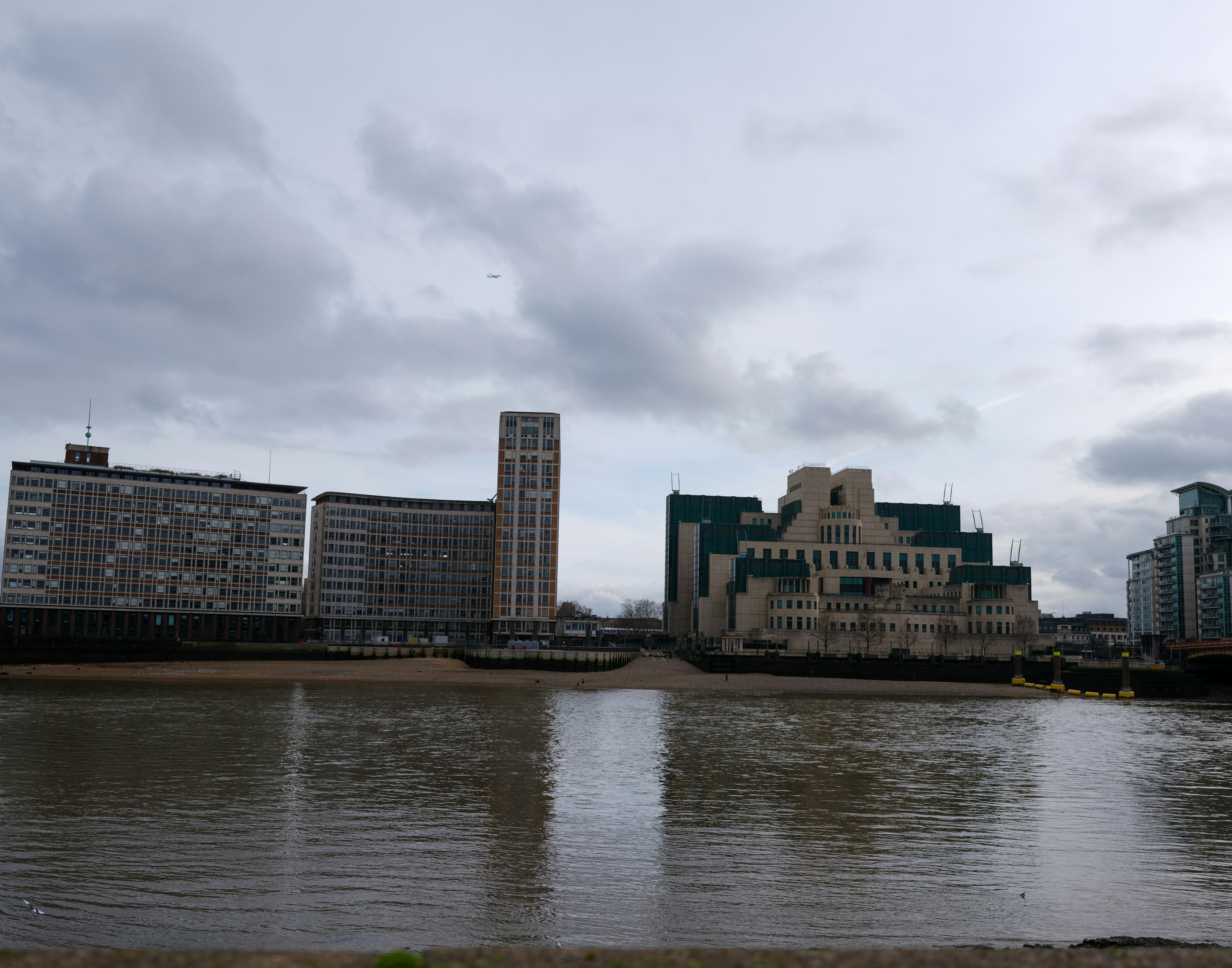Buildings on the thames riverbank under a cloudy sky.