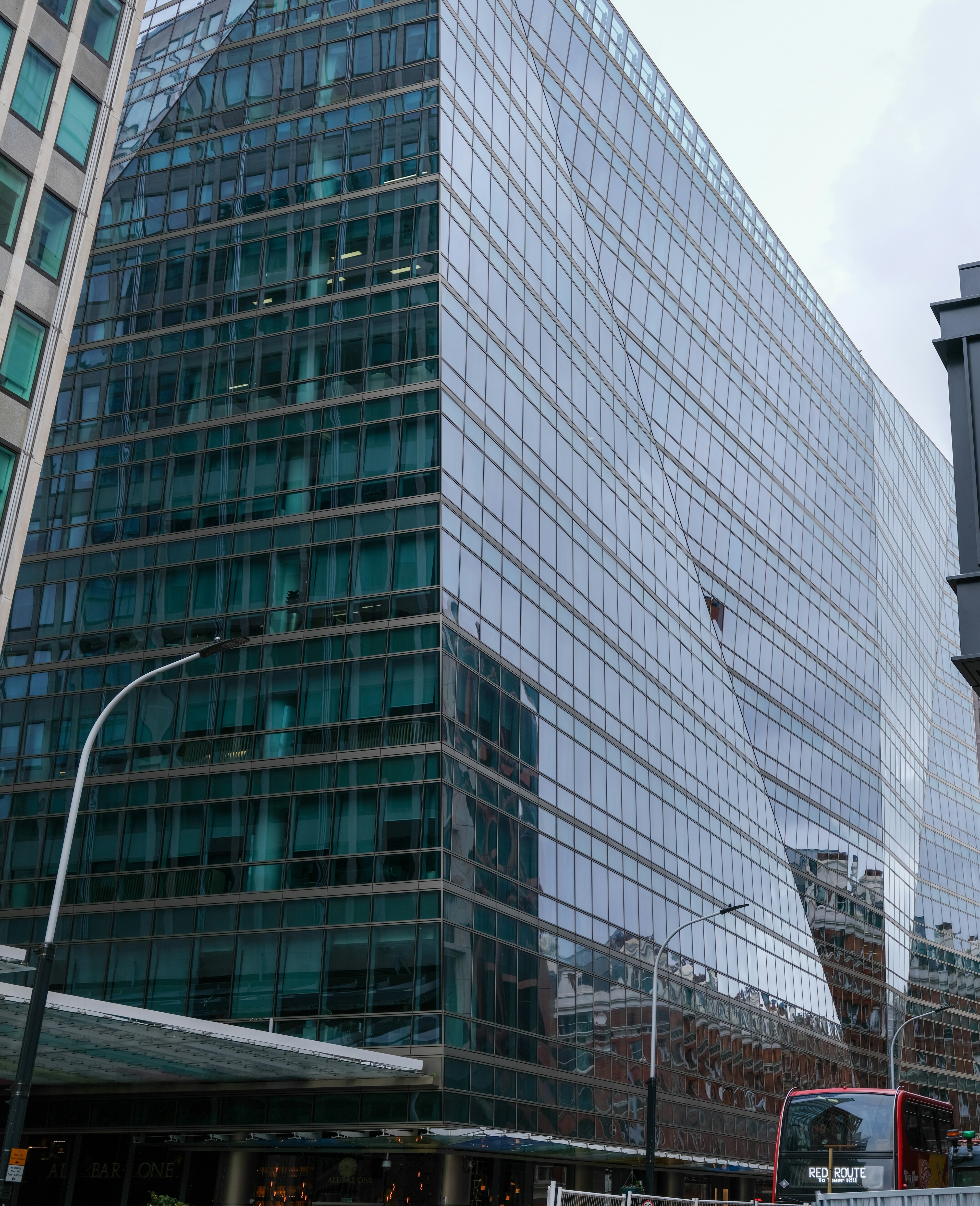 Modern glass building with angled facade and street view.