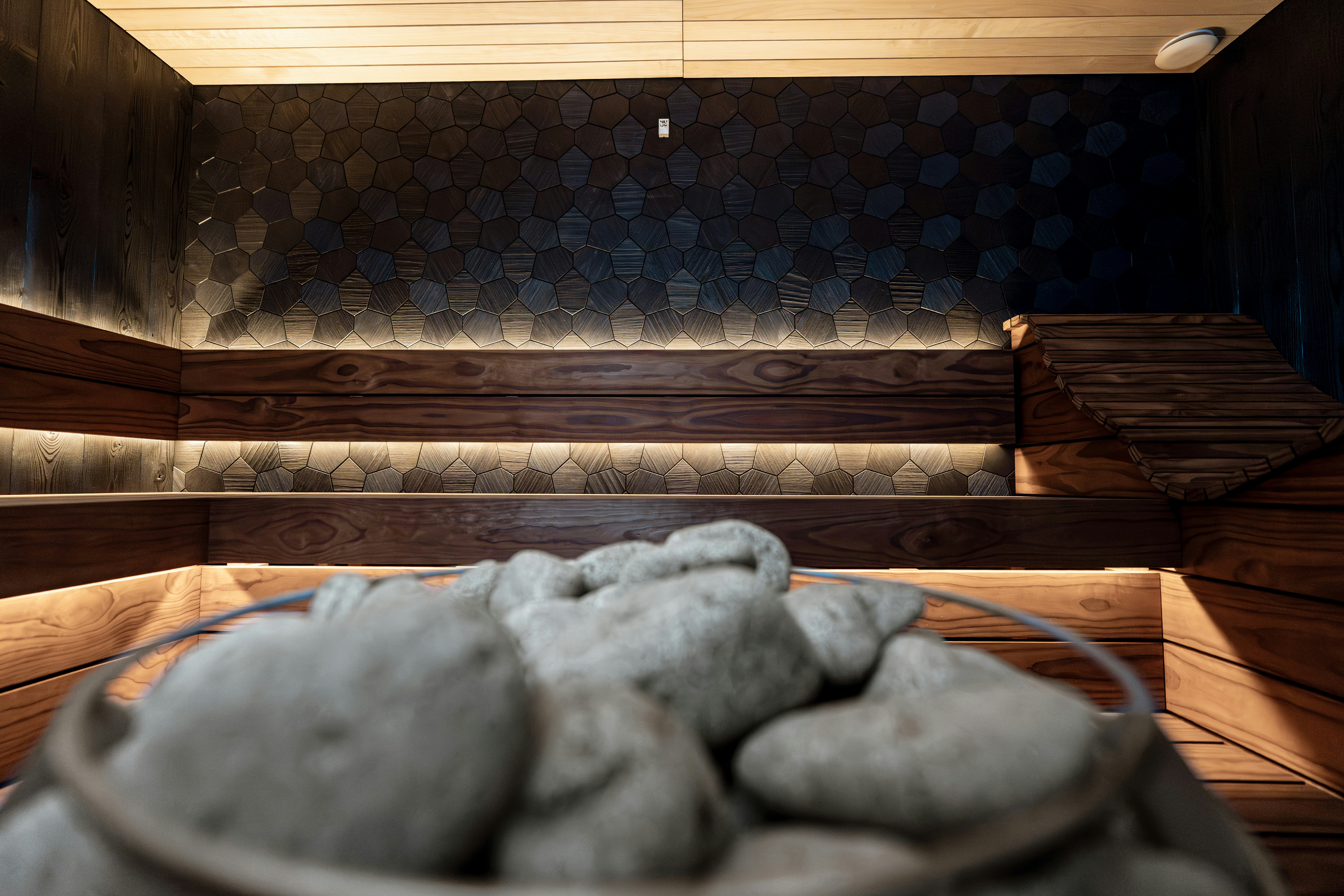 A modern sauna interior with wooden benches and hot stones