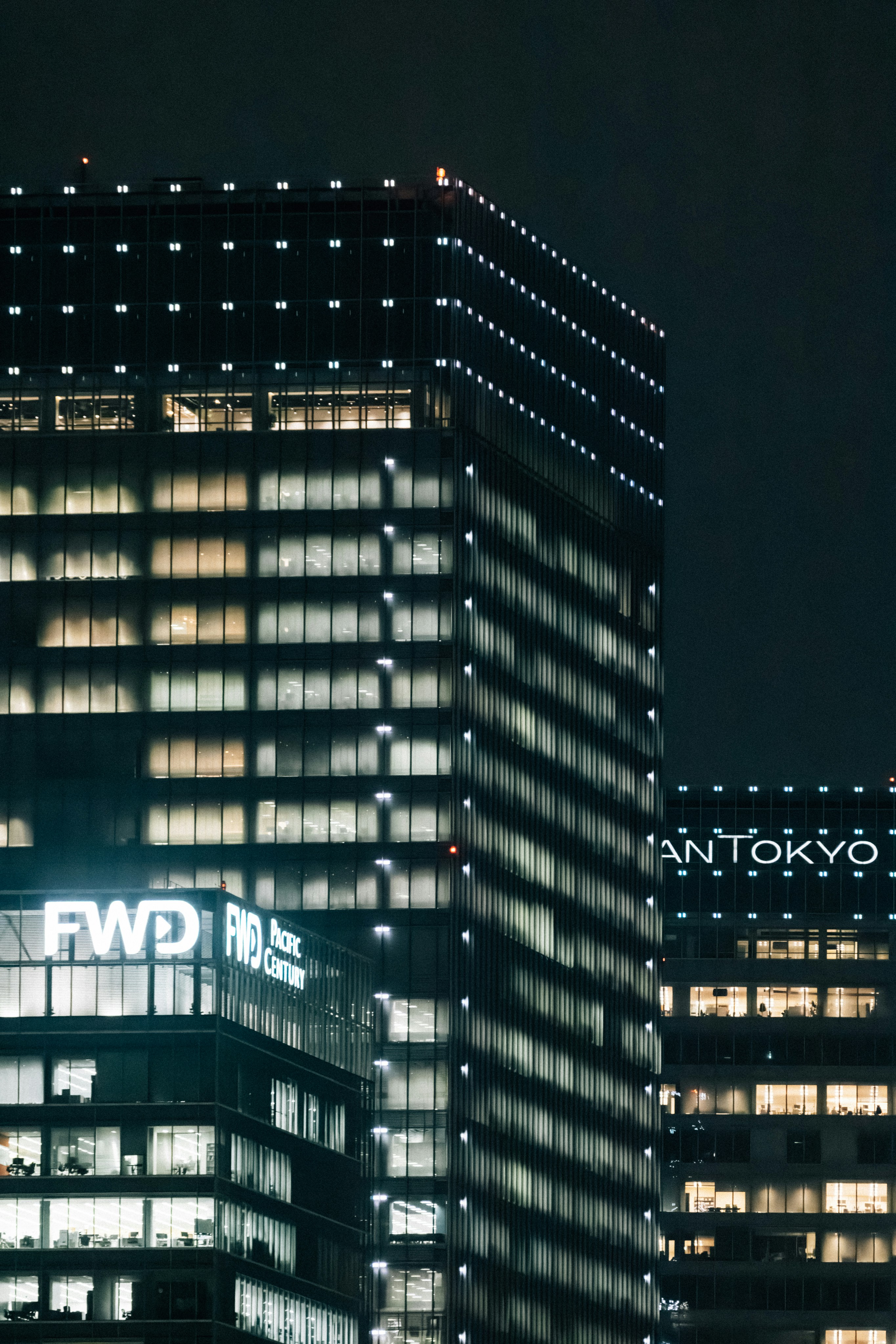 Illuminated skyscrapers at night with city lights.