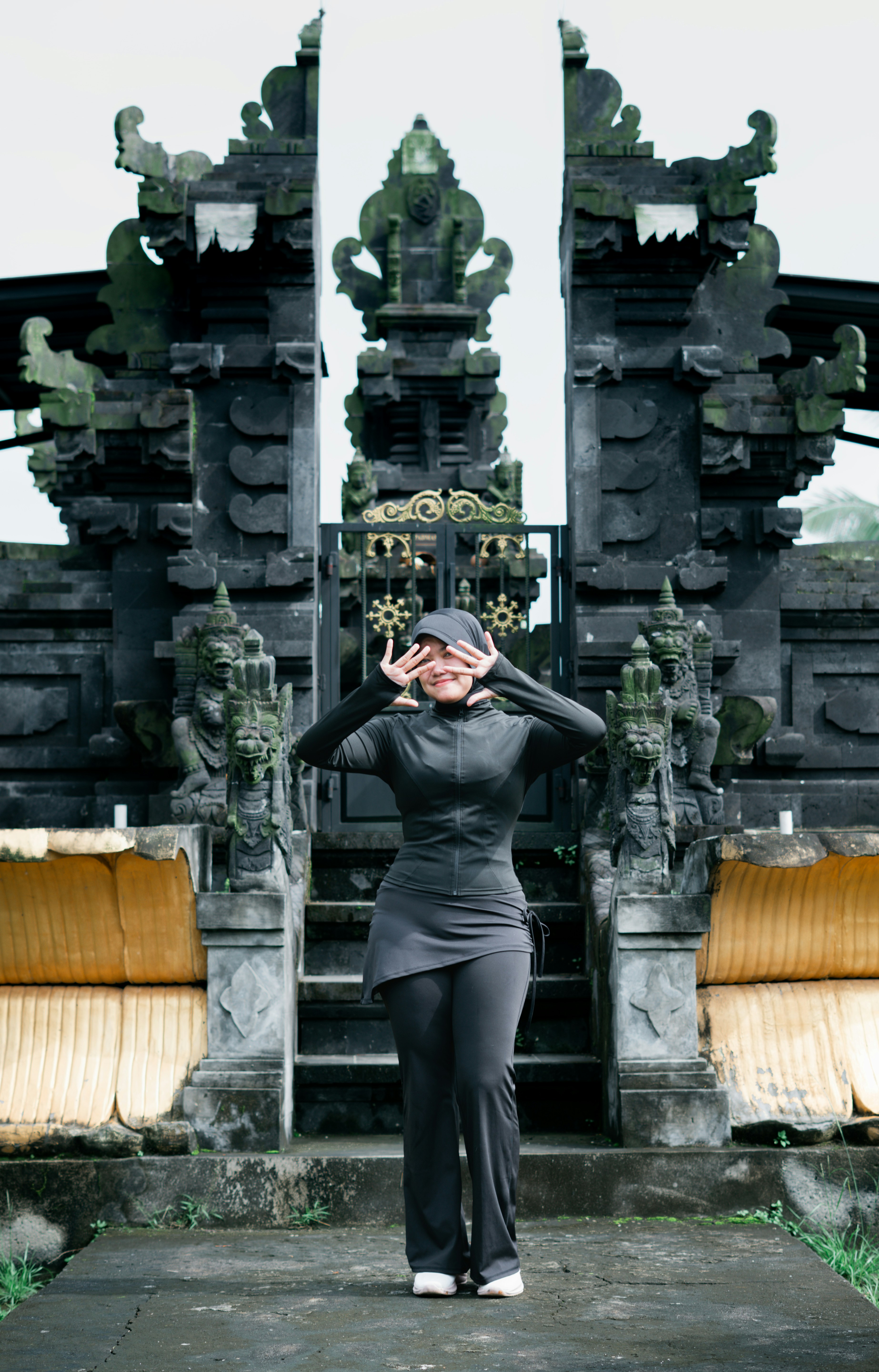 Woman posing in front of ornate temple gates
