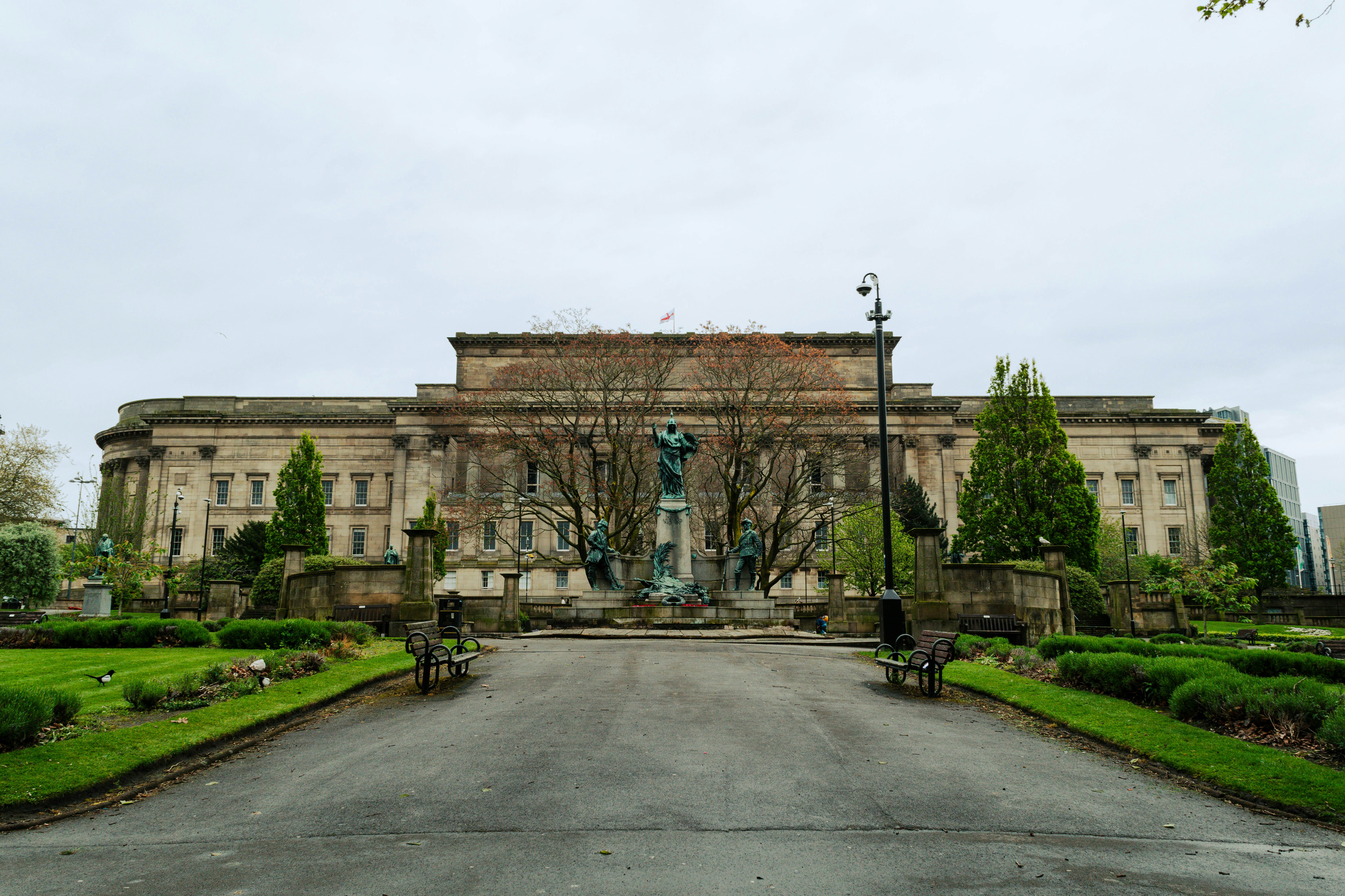 Grand bâtiment en pierre avec jardins et arbres soignés