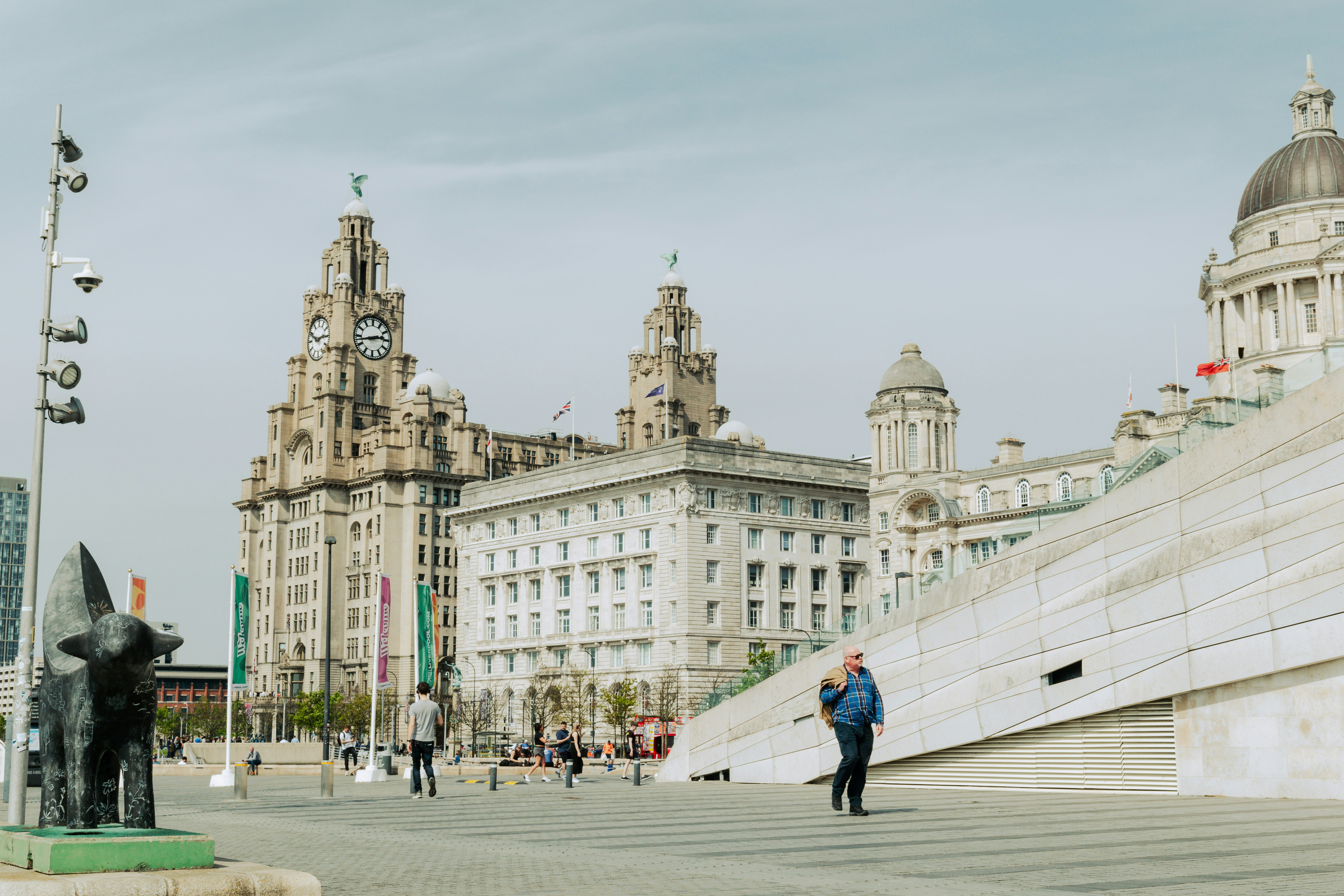 Des gens se promenant sur une promenade avec des bâtiments historiques derrière.