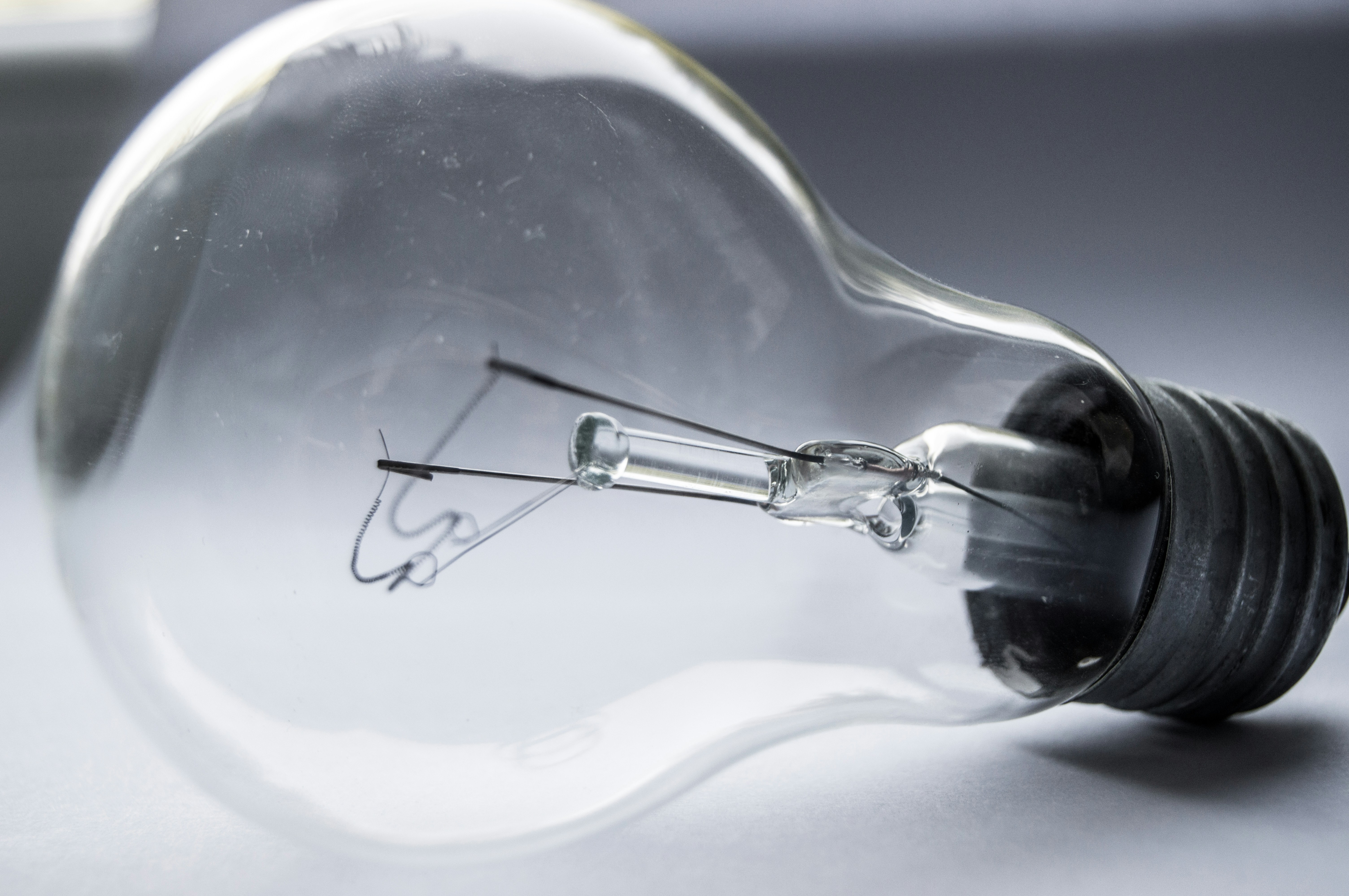 A clear glass light bulb on a gray surface.
